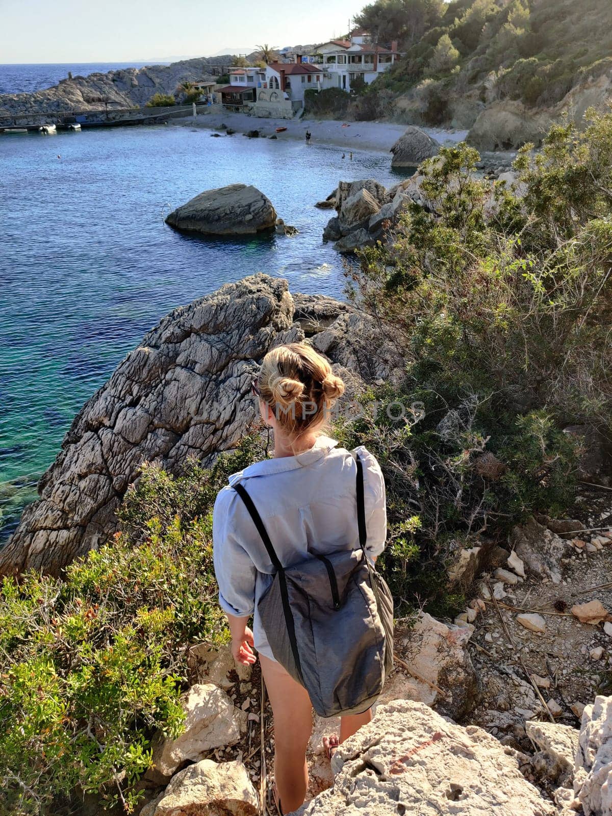 Young active feamle tourist wearing small backpack walking on coastal path among pine trees enjoing beautiful costal view of Velo Zarace beach on Hvar island, Croatia. Travel and adventure concept.