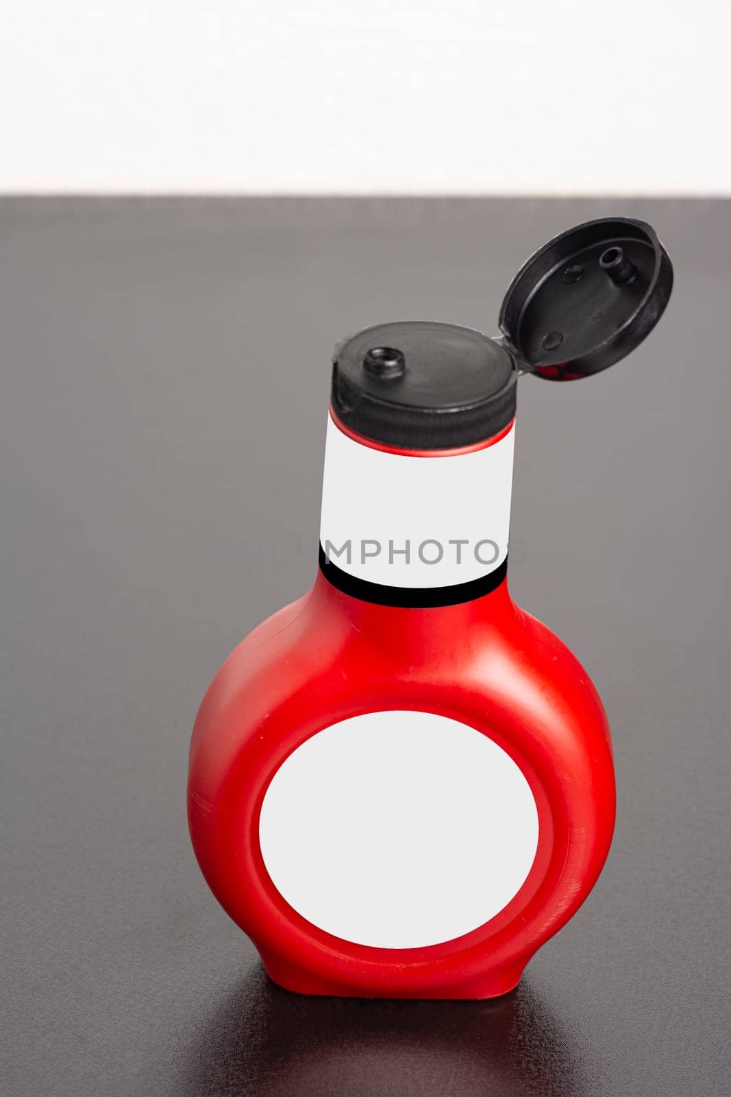 Tomato sauce bottle with cap on black table, editable mock-up series template ready for your design, selection path included.