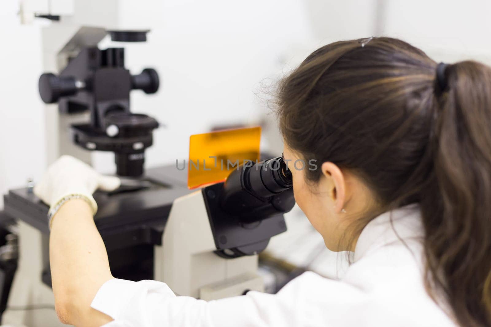 Life science female researcher microscoping in scientific genetic laboratory. Healthcare and biotechnology.