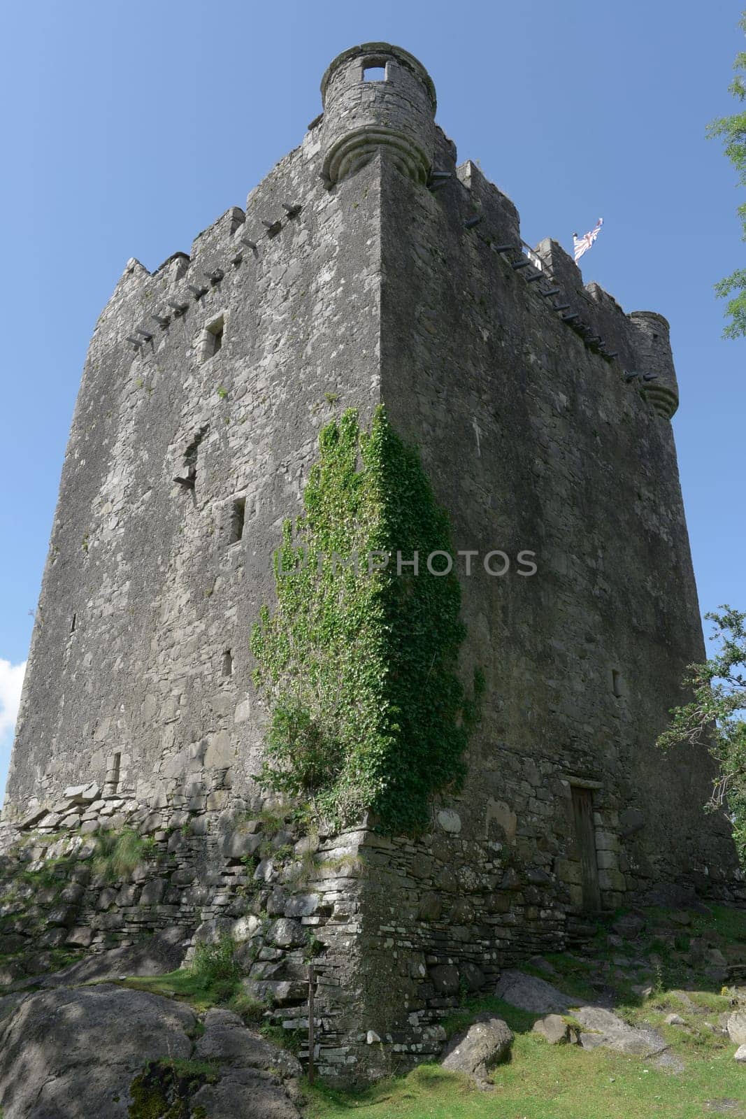 Sun and shade contrast across the imposing vertical exterior walls of moy castle near lochbuie on the isle of mull. Blue skies and strong composition