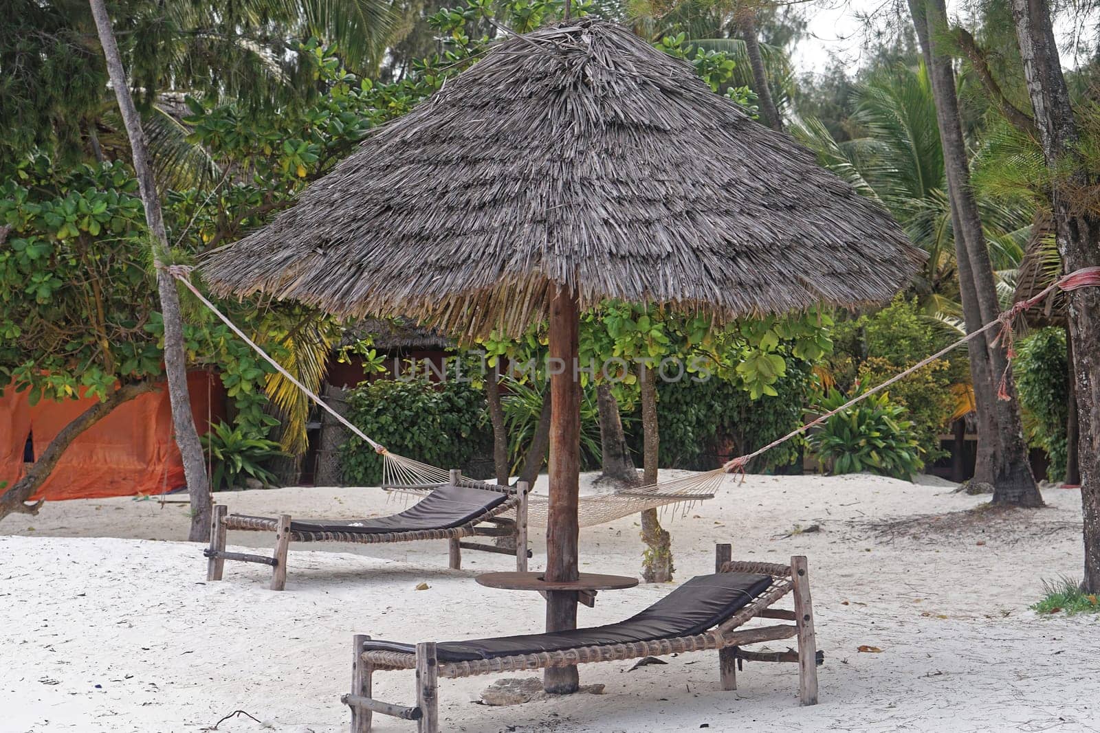 Beach bed under palm parasol at white sand