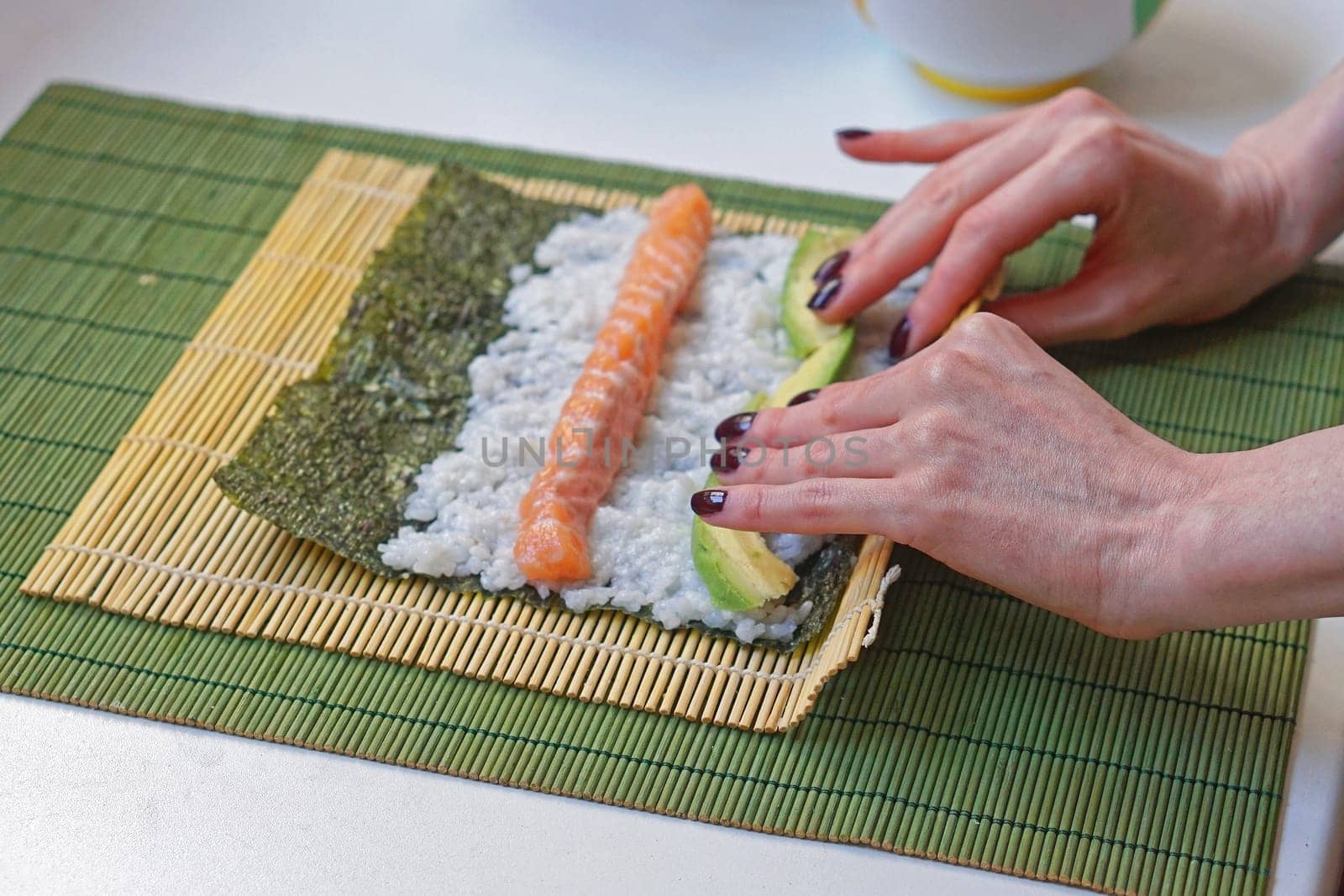 Woman rolling sushi with bamboo mat