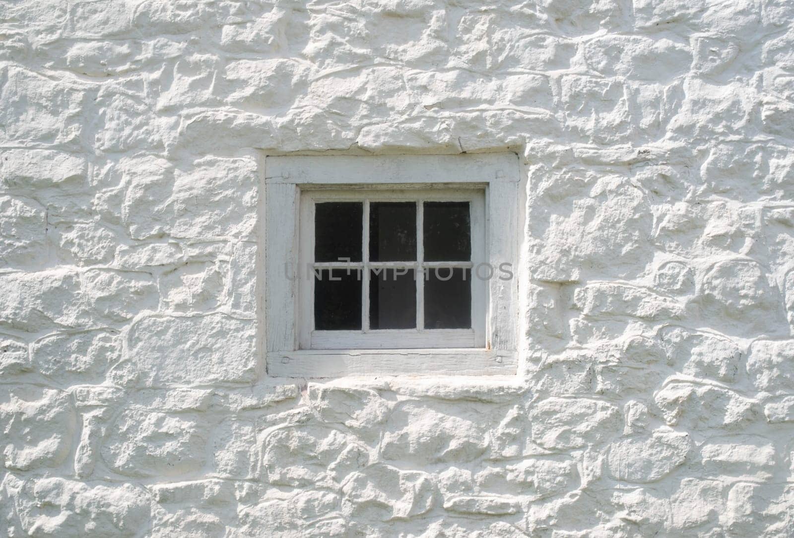 Ancient construction style using wooden dowels and six-pane glass. Fresh whitewash on stone facade.