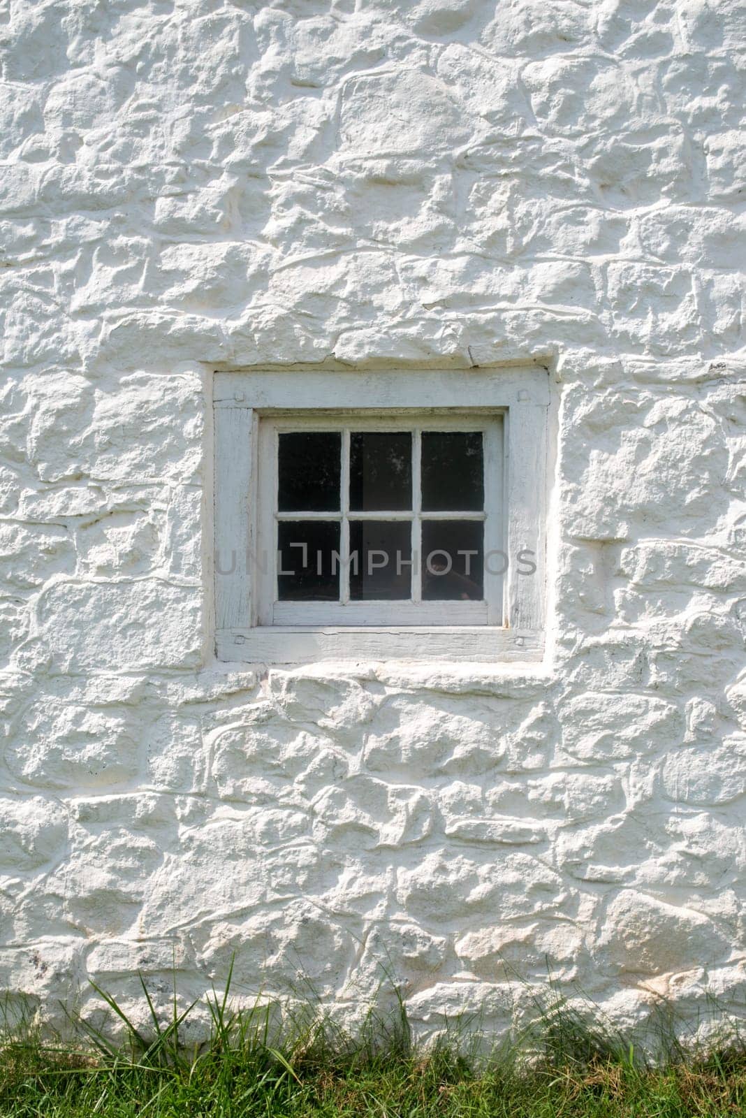 Whitewashed stone gleams in natural light with antique glass window and window frame made with wooden dowels.