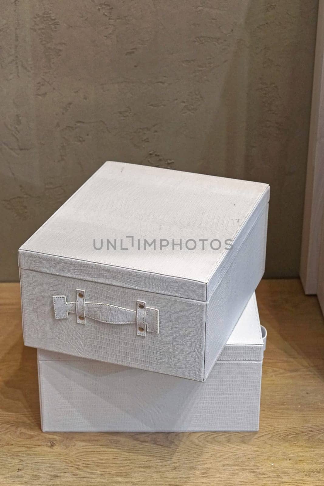Two white boxes stacked at wooden floor