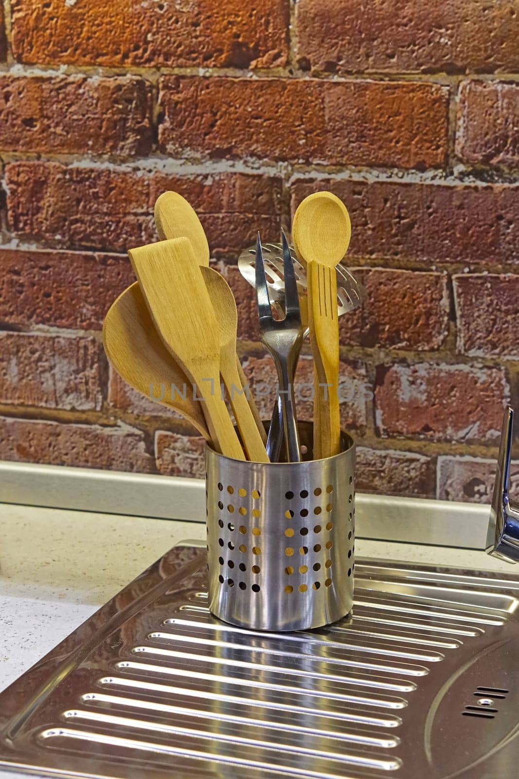 Can of kitchen utensils at stainless steel sink