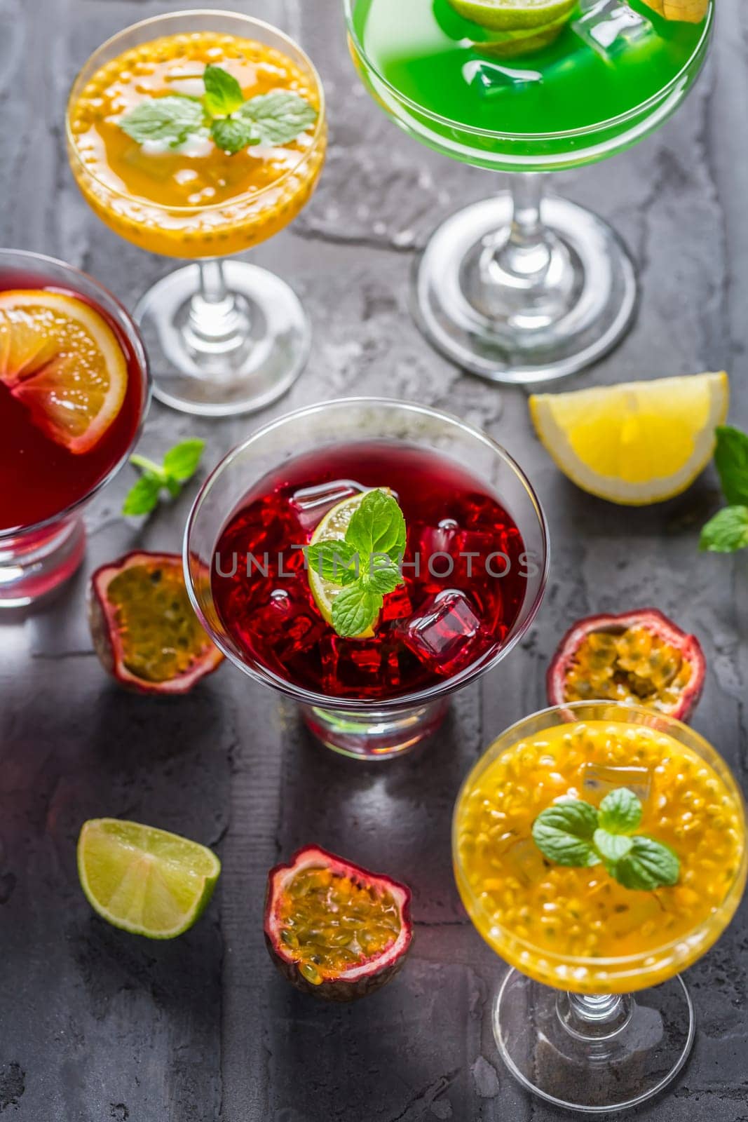 Assortment of different cocktails with fresh fruits, ice and mint on black background.