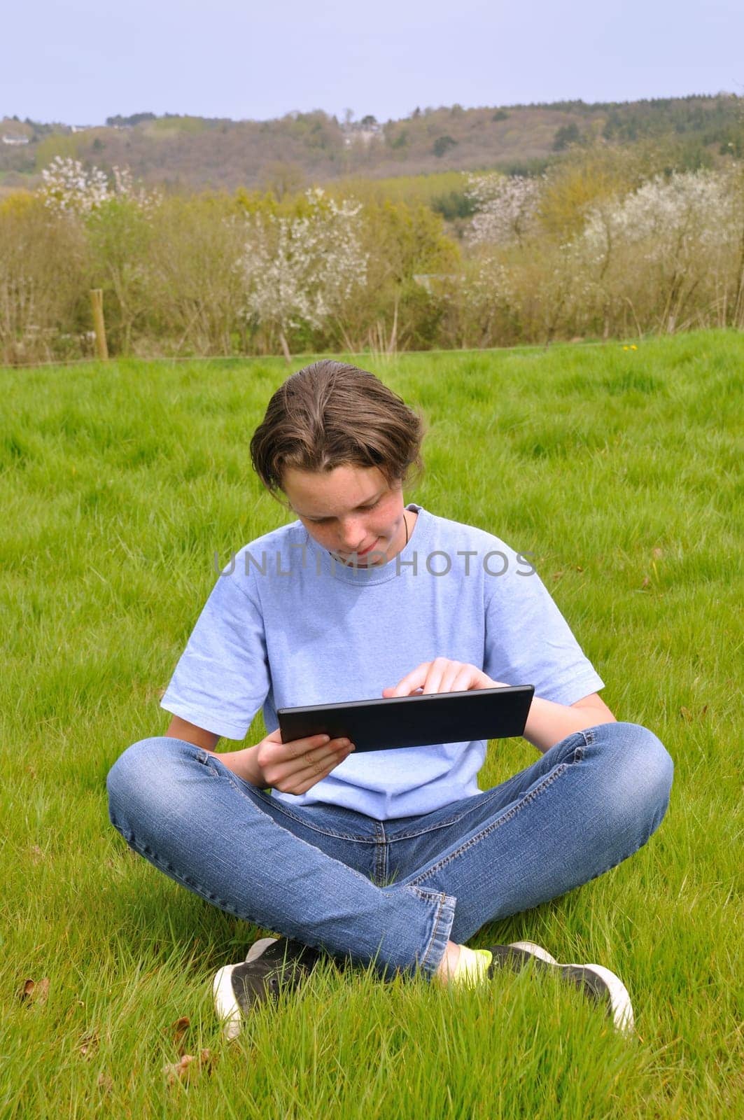 Girl sitting on the lawn and using digital tablet