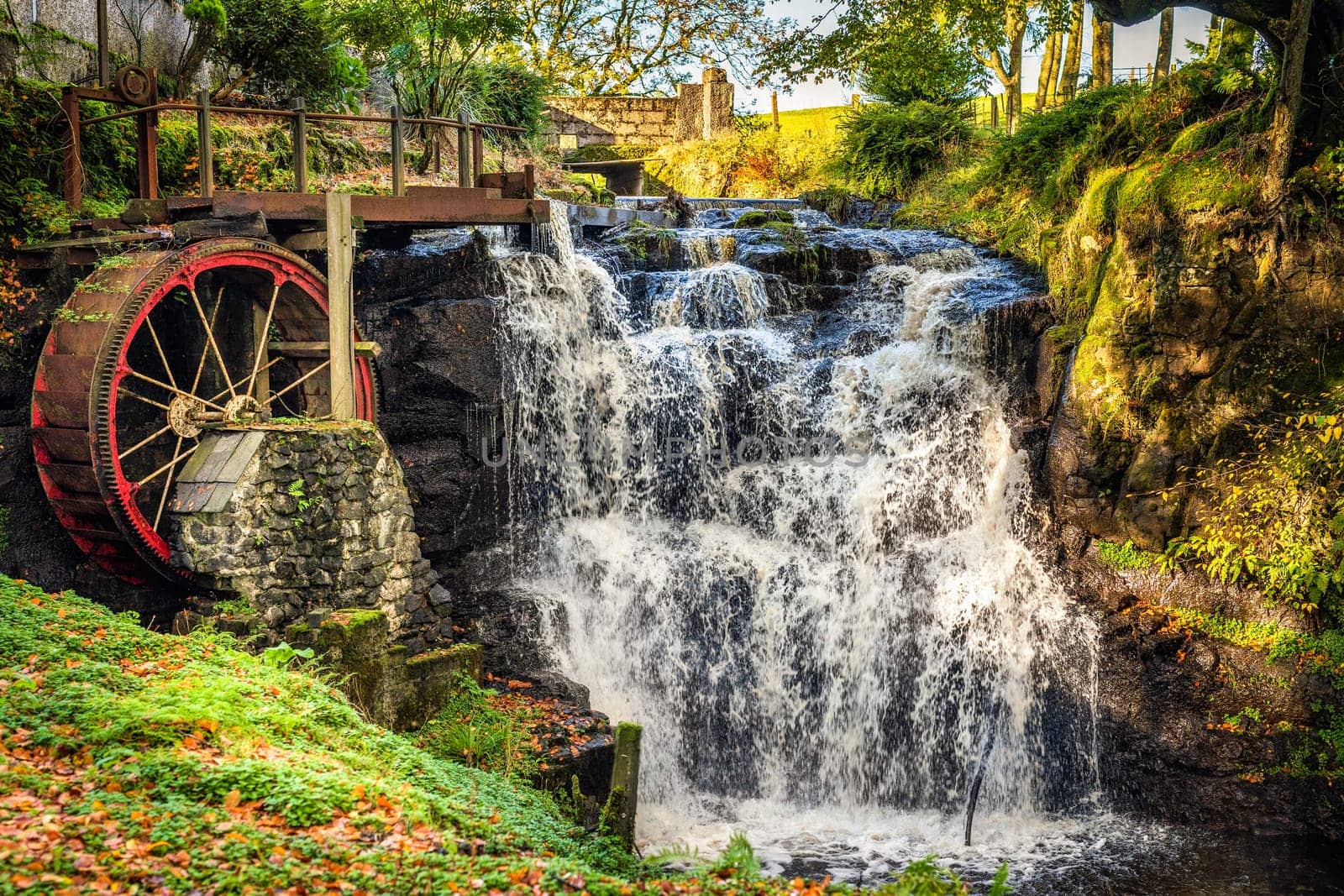 Vintage red waterwheel with waterfall in autumn colours in Glenariff Forest Park, Count Antrim, Northern Ireland