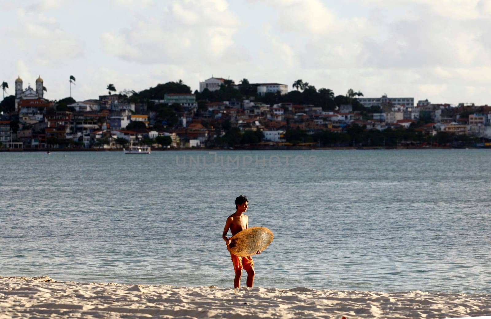 salvador, bahia / brazil - august 12, 2015: young man is seen surfing with a piece of wood on Ribeira beach in the city of Salvador.