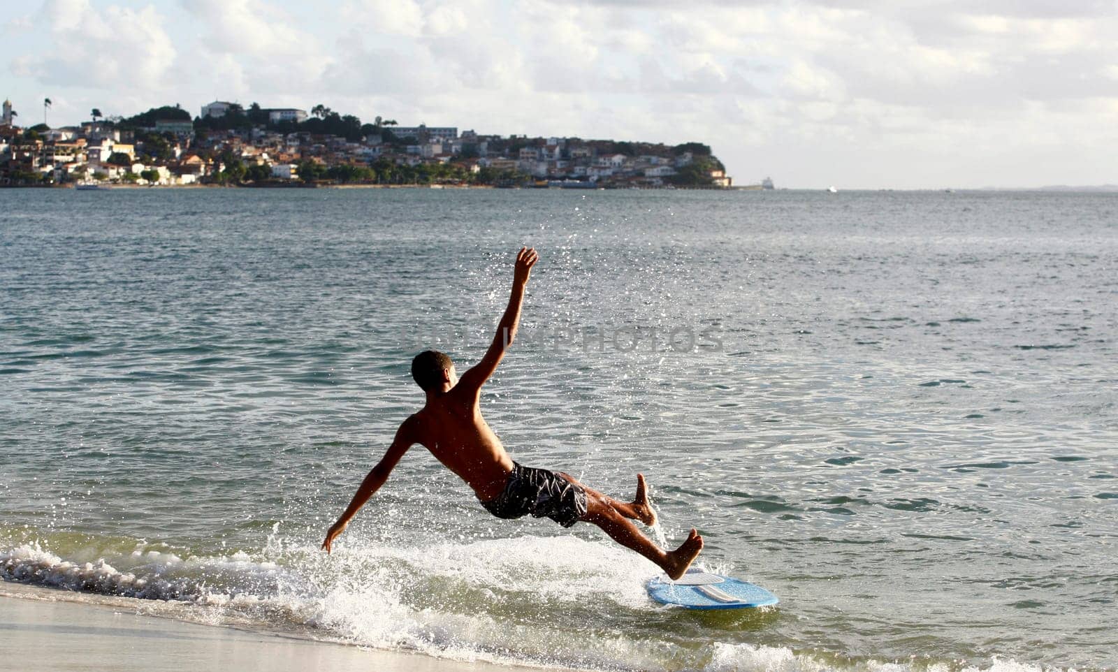 salvador, bahia / brazil - august 12, 2015: young man is seen surfing with a piece of wood on Ribeira beach in the city of Salvador.