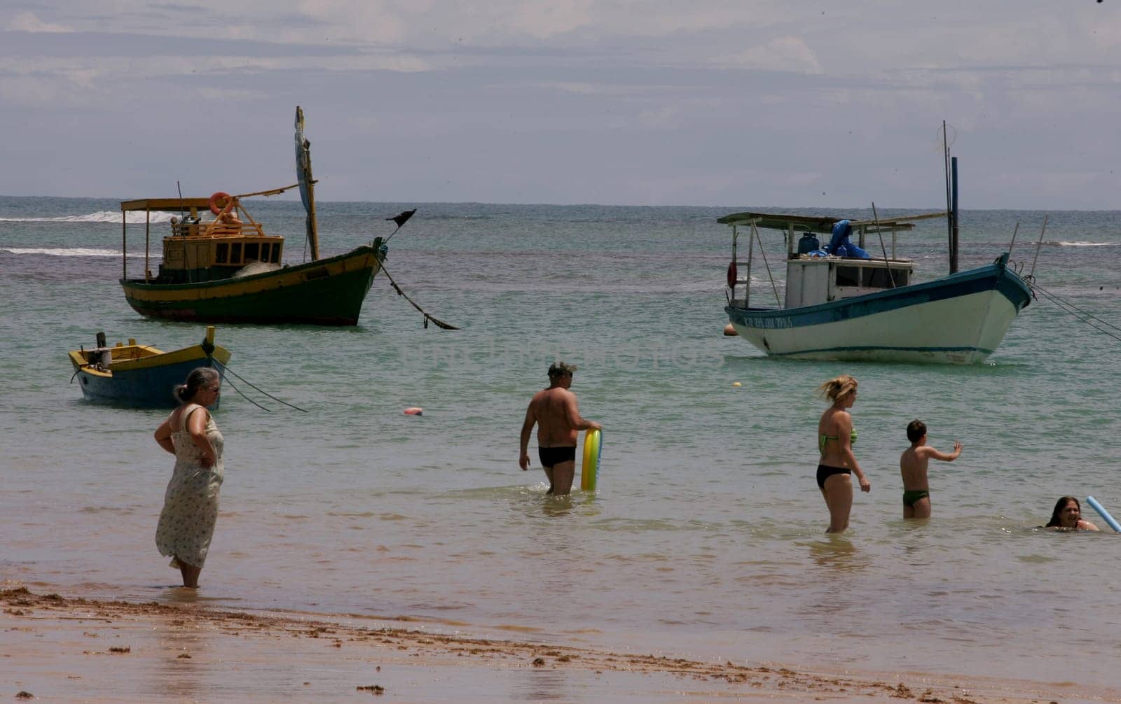 porto seguro, bahia / brazil - january 7, 2011: Fishing boat is seen with people on the beach in the city of Porto Seguro, in southern Bahia.