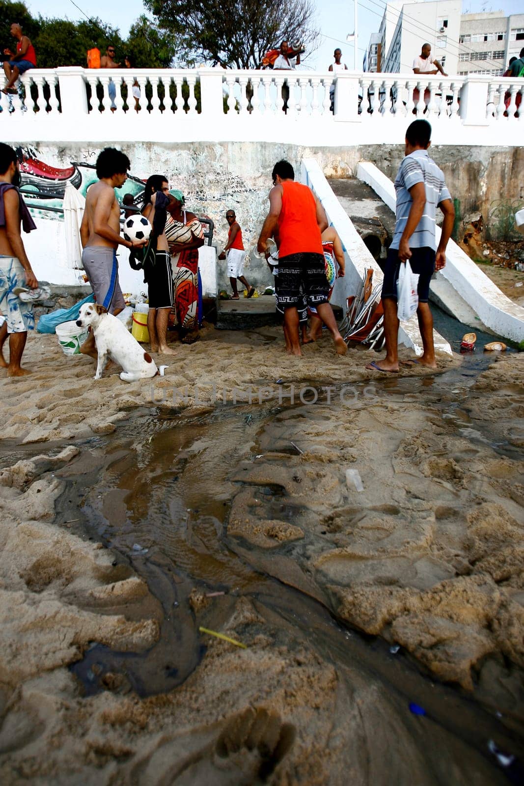 salvador, bahia / brazil - november 4, 2015: people are seen by the open sewage water gushing in the sand of Porto da Barra in the city of Salvador.