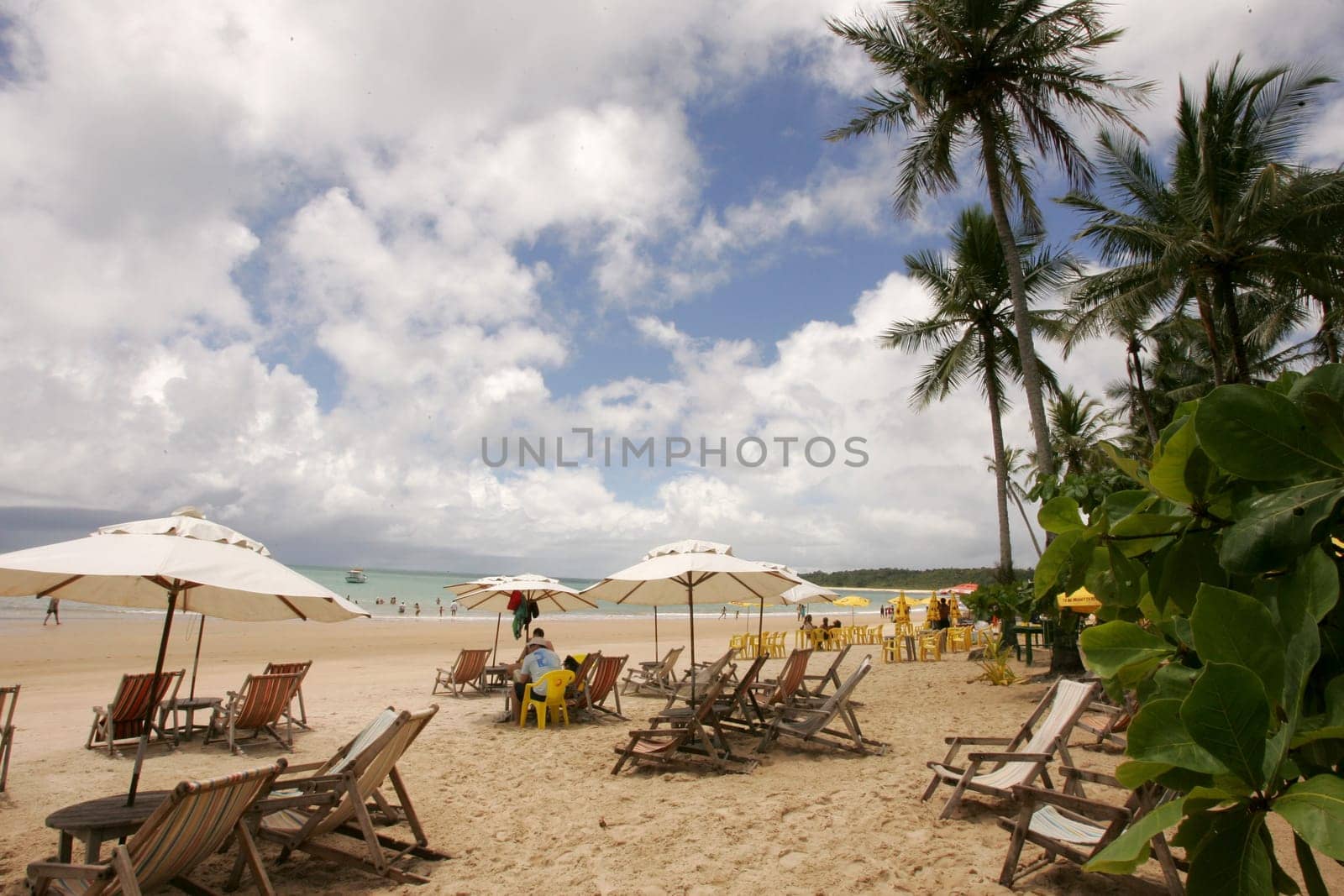 porto Seguro, bahia / brazil - january 7, 2011: people are seen sitting next to chairs on the beach of Trancoso in the city of Porto Seguro, in the south of Bahia.