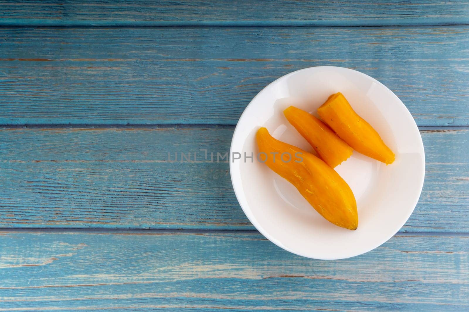 Ubi rebus or steam cassava is traditional malay dish on wooden background. Selective focus
