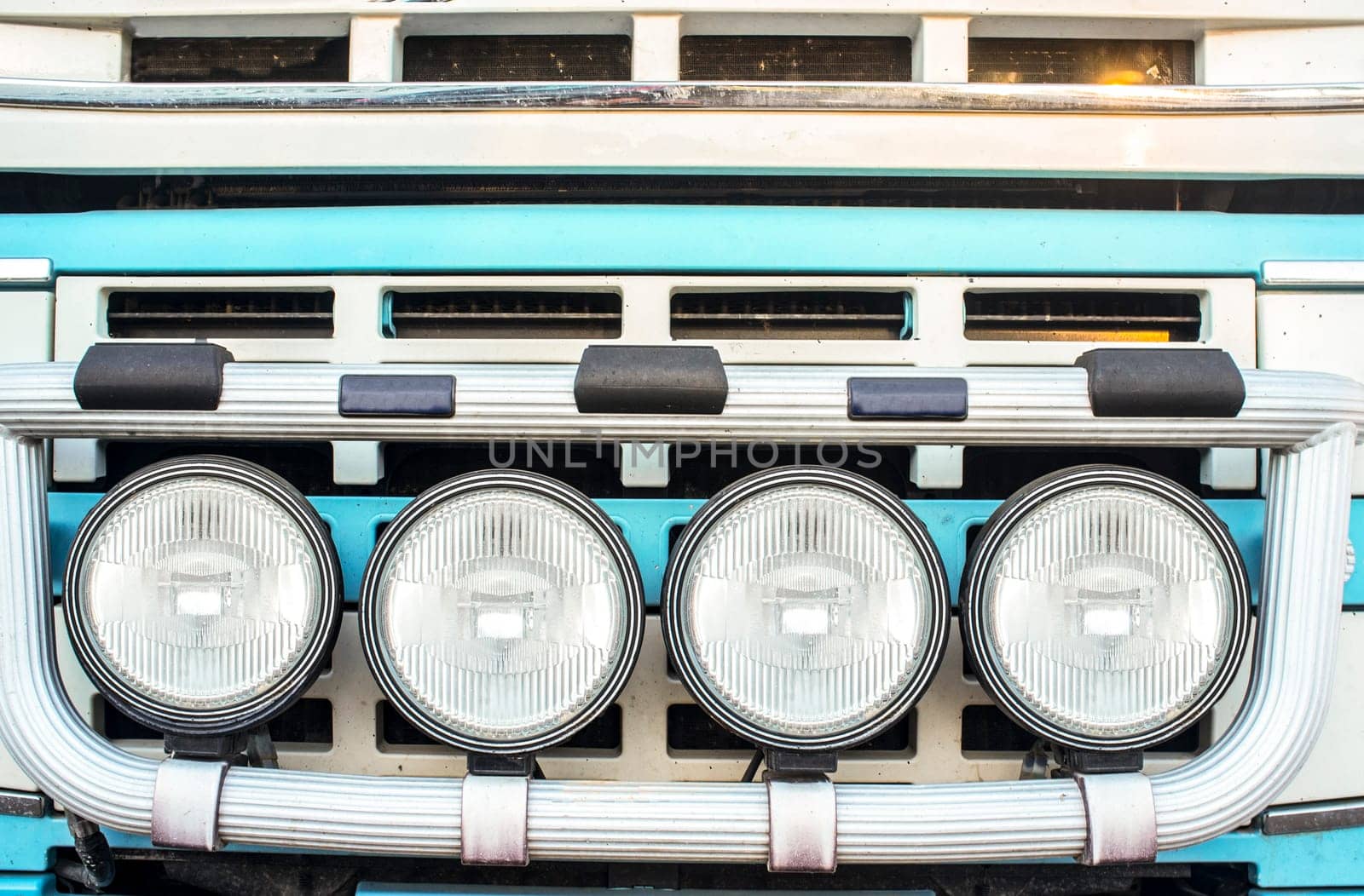 Tractor truck radiator grid protected with bumper-mounted offroad spotlights. Blue arctic painted