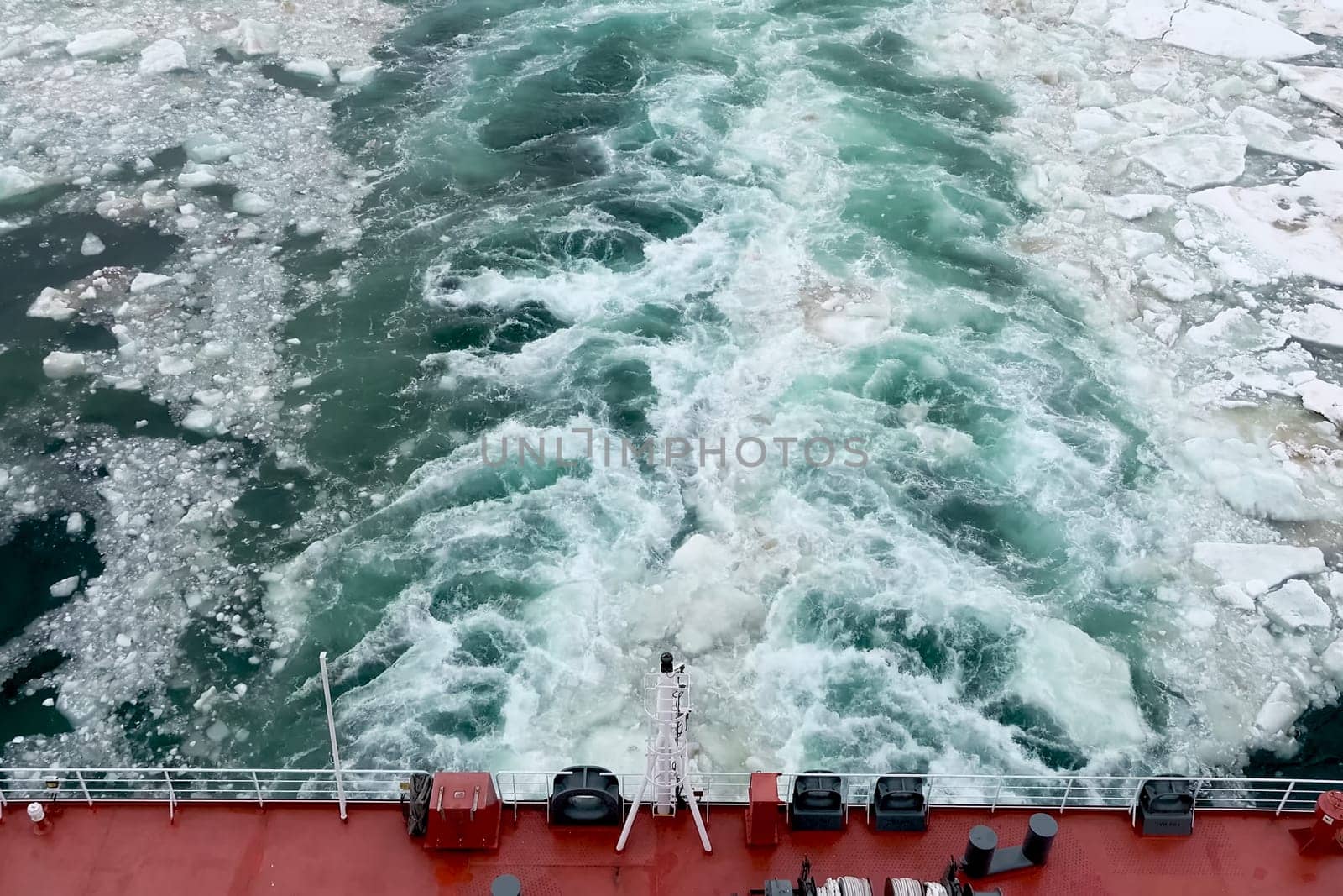 A trail on the water from the ship. Arctic and ice on the water. The propellers of the ship smeared the water.