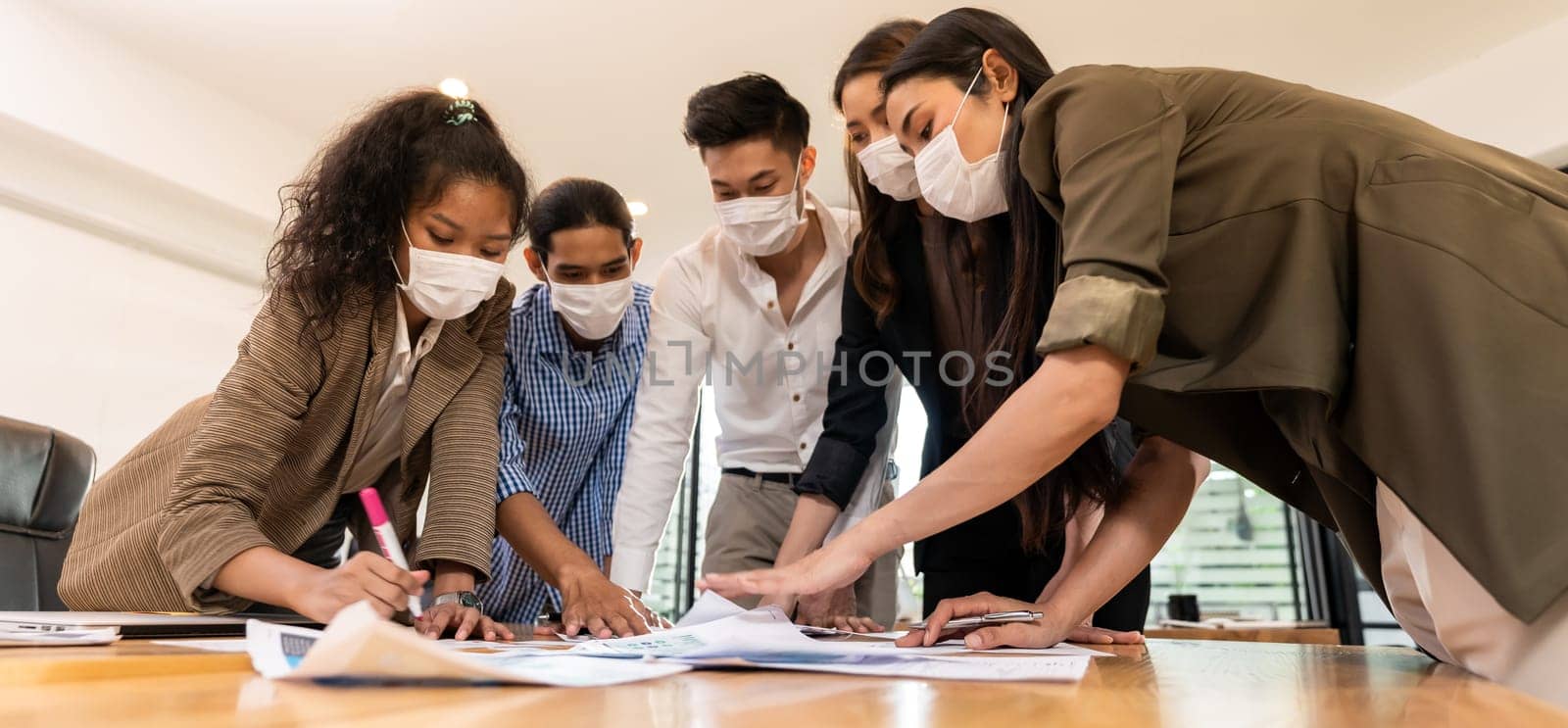 Panorama Interracial asian business team brainstorming idea at office meeting room after reopen due to coronavirus COVID-19. They wear face mask reduce risk to infection as new normal lifestyle.