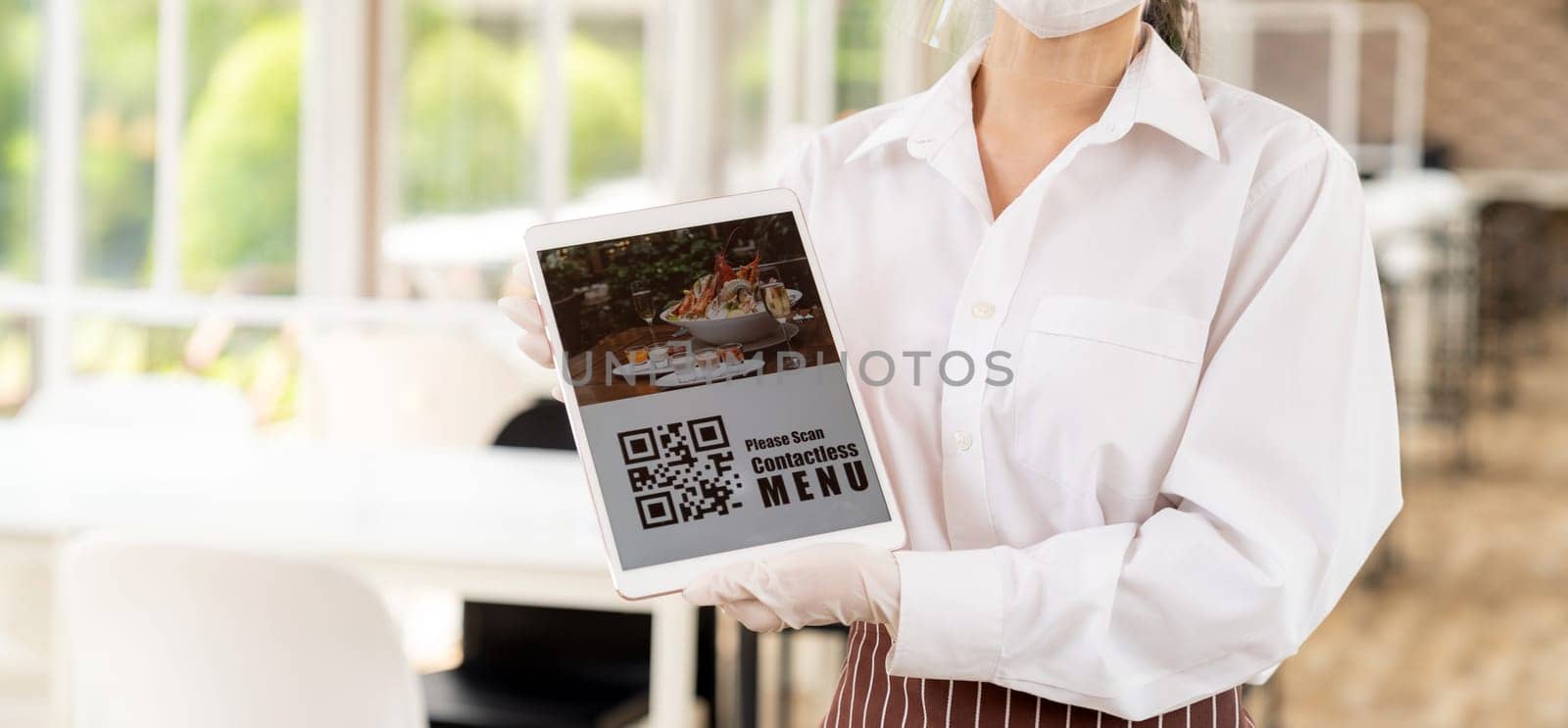 Panorama close up waitress with face mask and face shield hold digital tablet with QR code for customer to scan for online contactless menu Contactless and technology concept for new normal restaurant