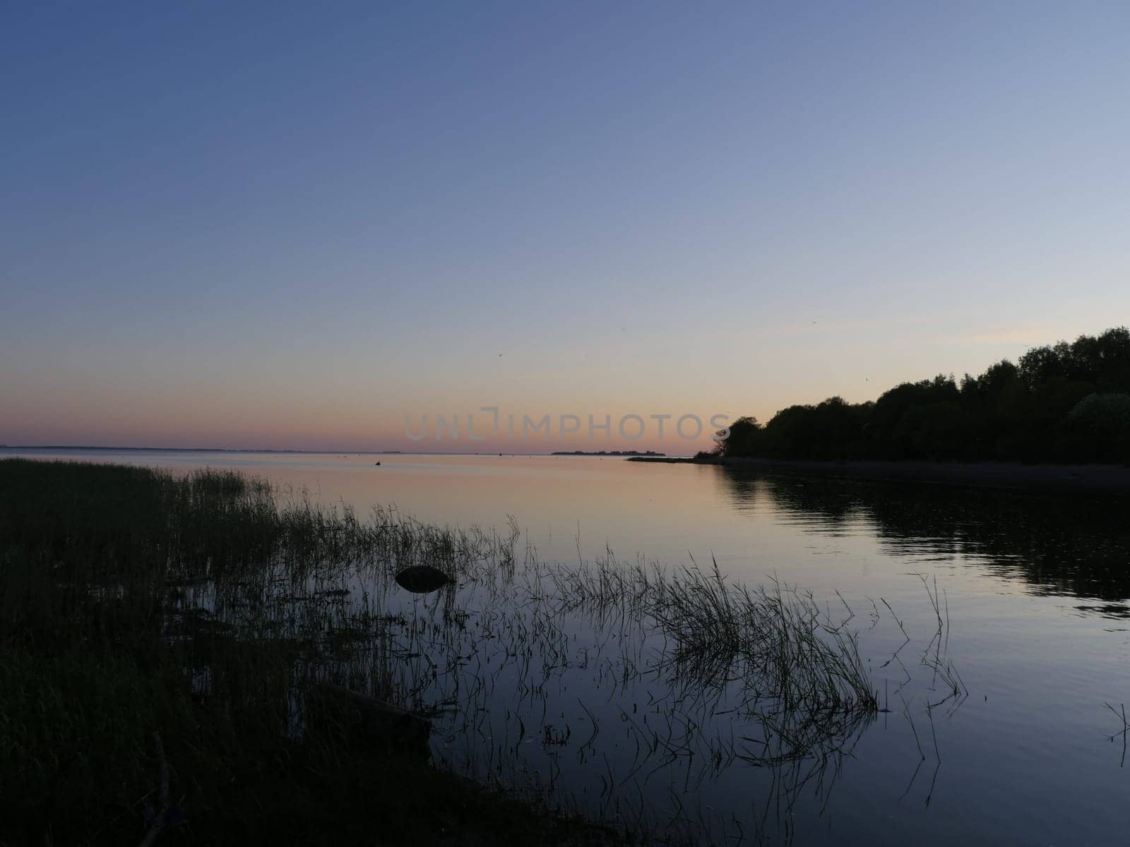 quiet evening on a blue lake, seascape illuminated by the sunset