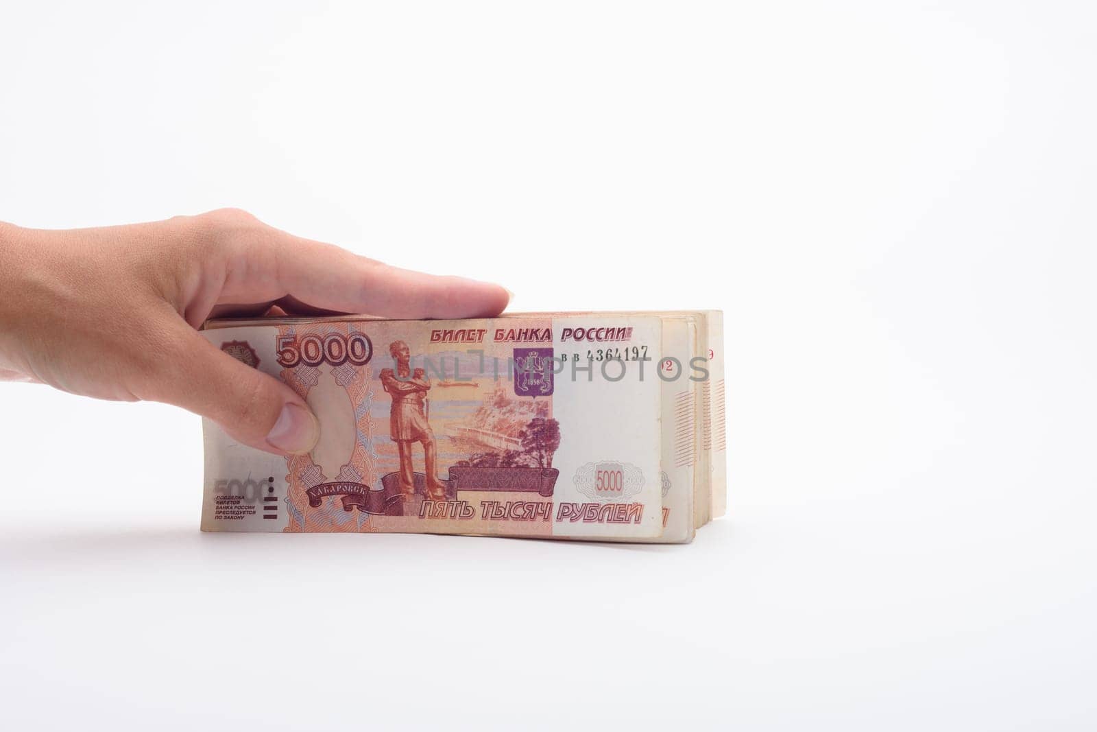 Hand holds a bundle of banknotes, five thousandth bills on a white background