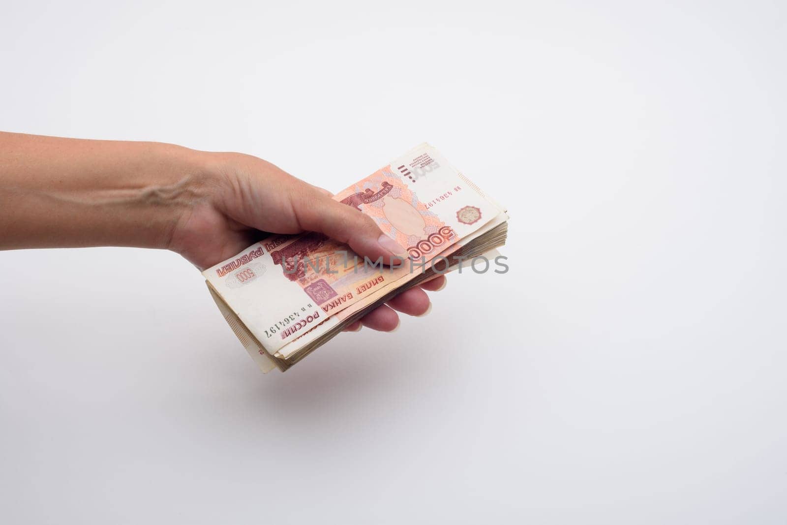 Hand holds out a stack of five thousandth bills