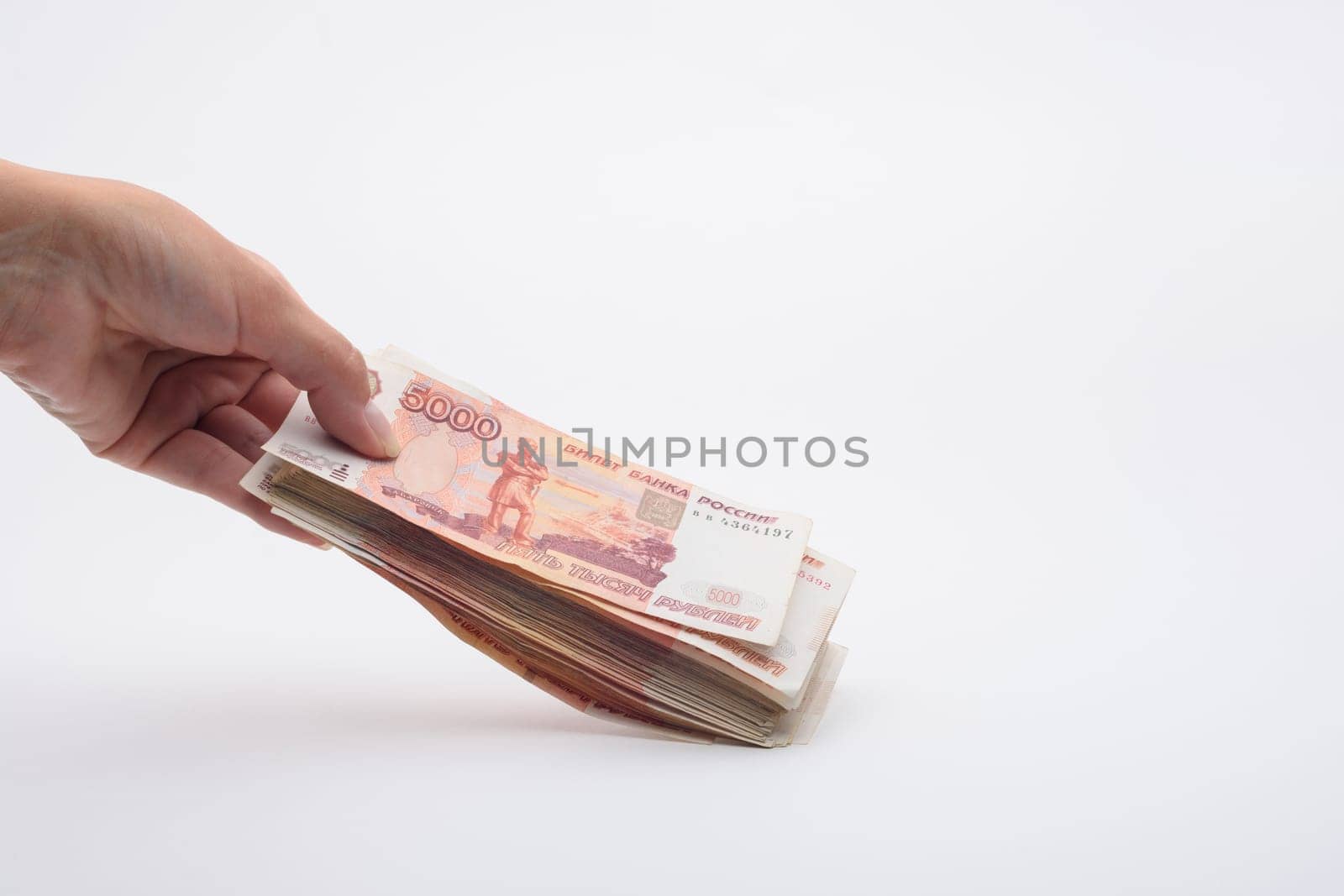 Hand holds out a bundle of five thousandth Russian banknotes
