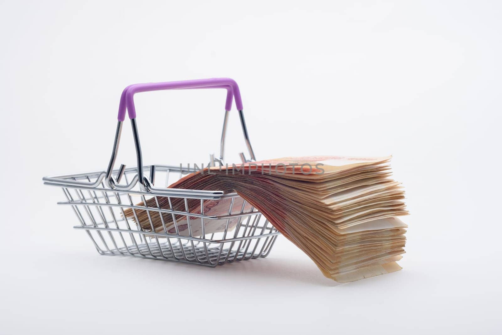 There is a large stack of bills on a grocery basket, viewed from the side