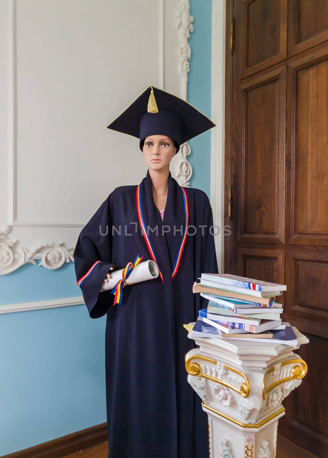 Student mannequin, inside a library, dressed as a graduate with a black academic cap and gown, holding a diploma in hand. Beautiful ornate ancient pillars with different books. Education concept.
