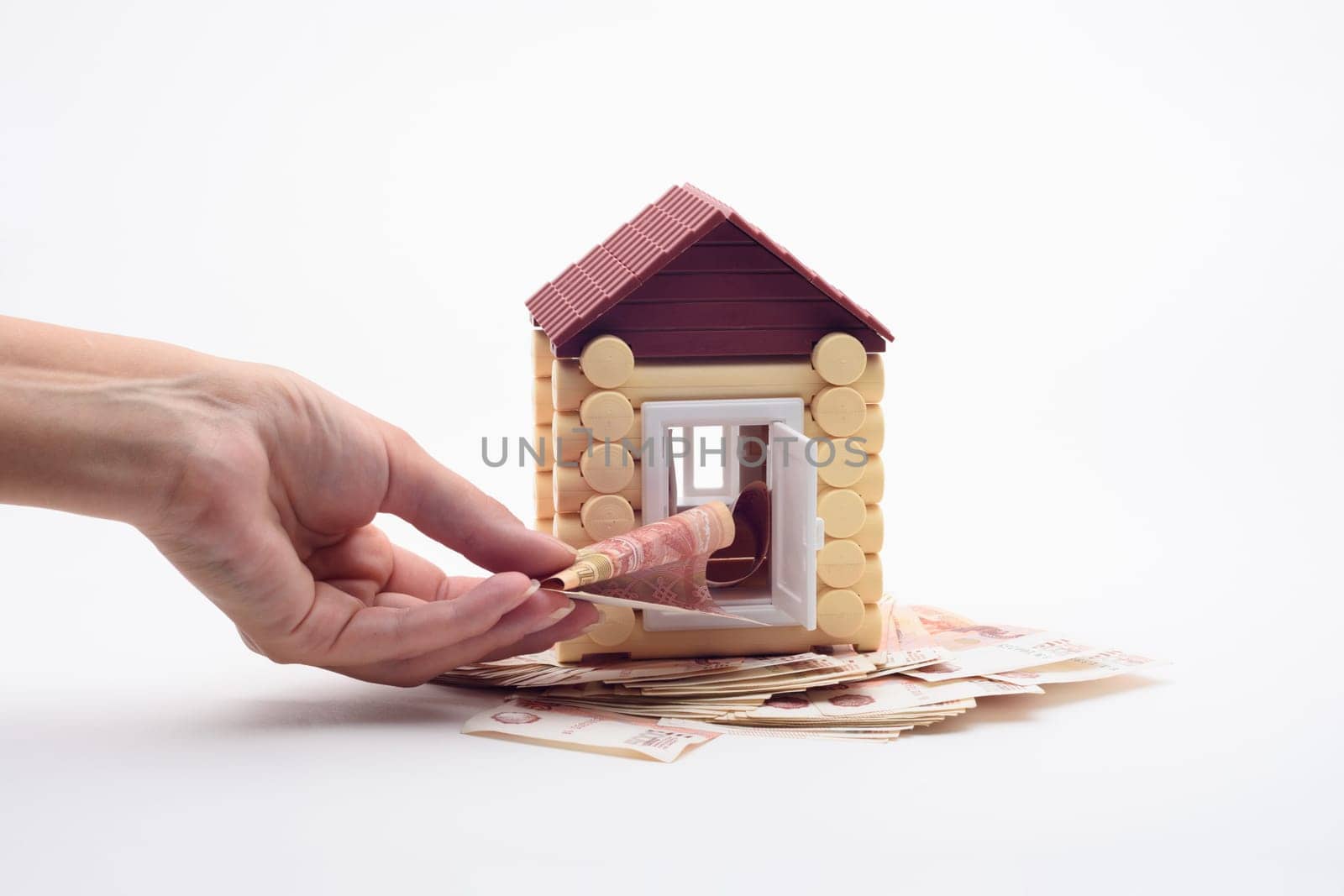 Hand puts a bill into the door of the toy house