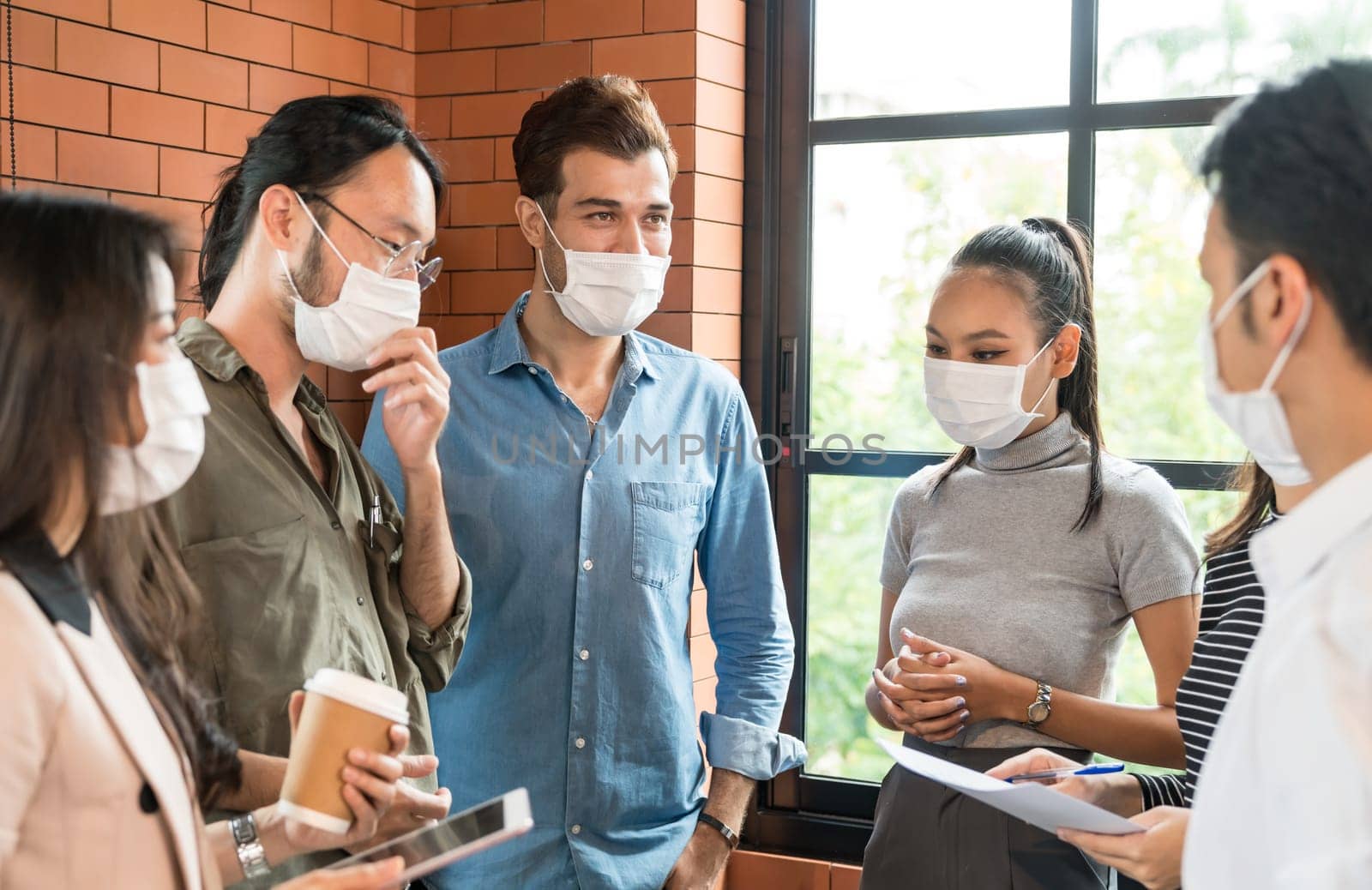 Group of business worker team meeting and brainstorm for startup new business. They wear protective face mask in new normal office preventing coronavirus COVID-19 spreading.