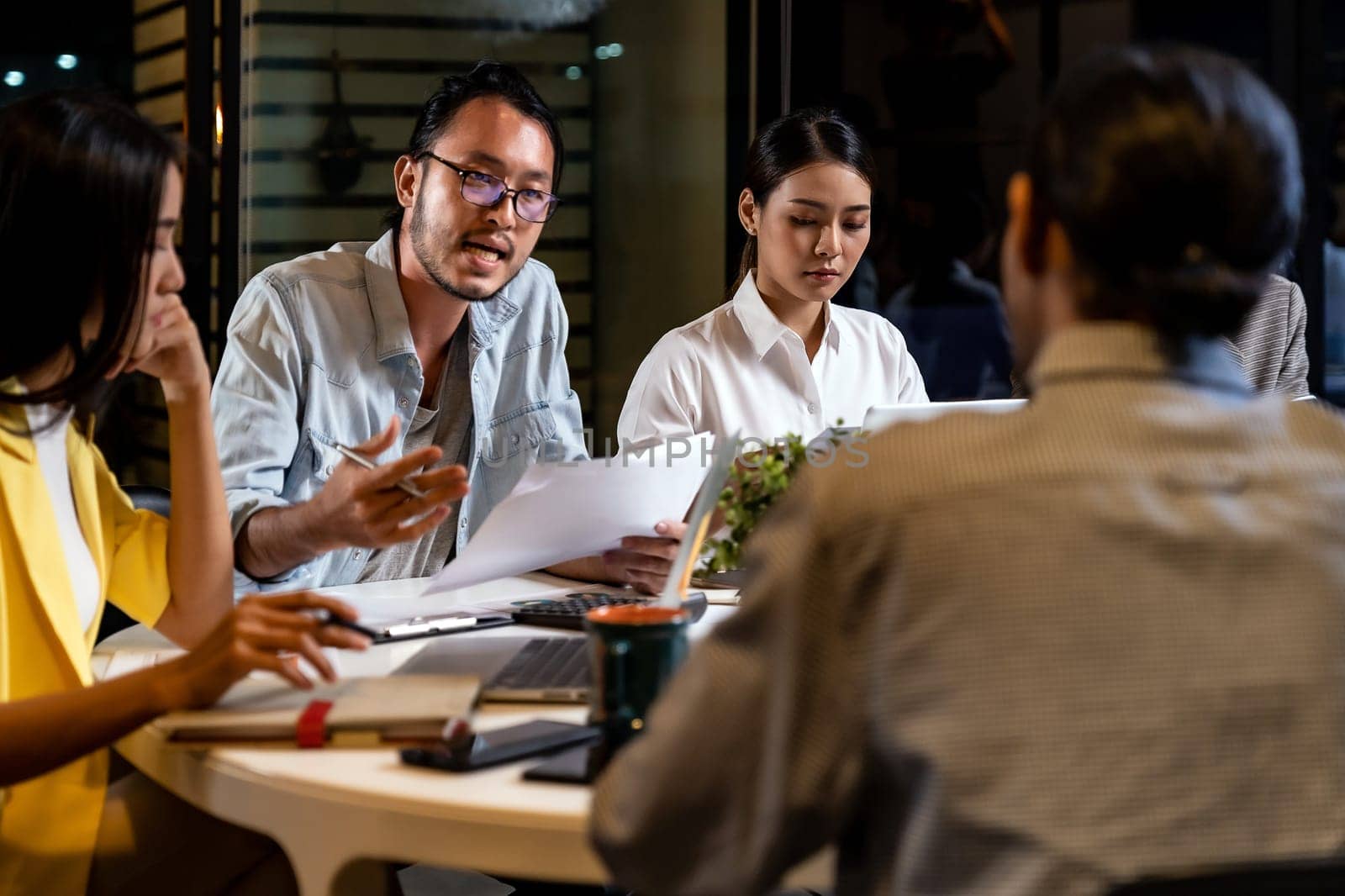 Work late concept of Interracial asian business team brainstorm idea at office meeting room at night. Work hard deadline and overtime working and new business start up concept.