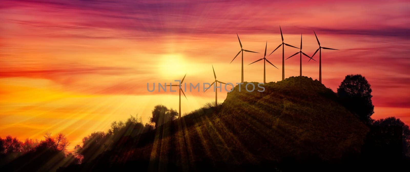 Horizontal composition of seven modern wind farms in the distance on a hill against the backdrop of a beautiful sunset in the evening as a background