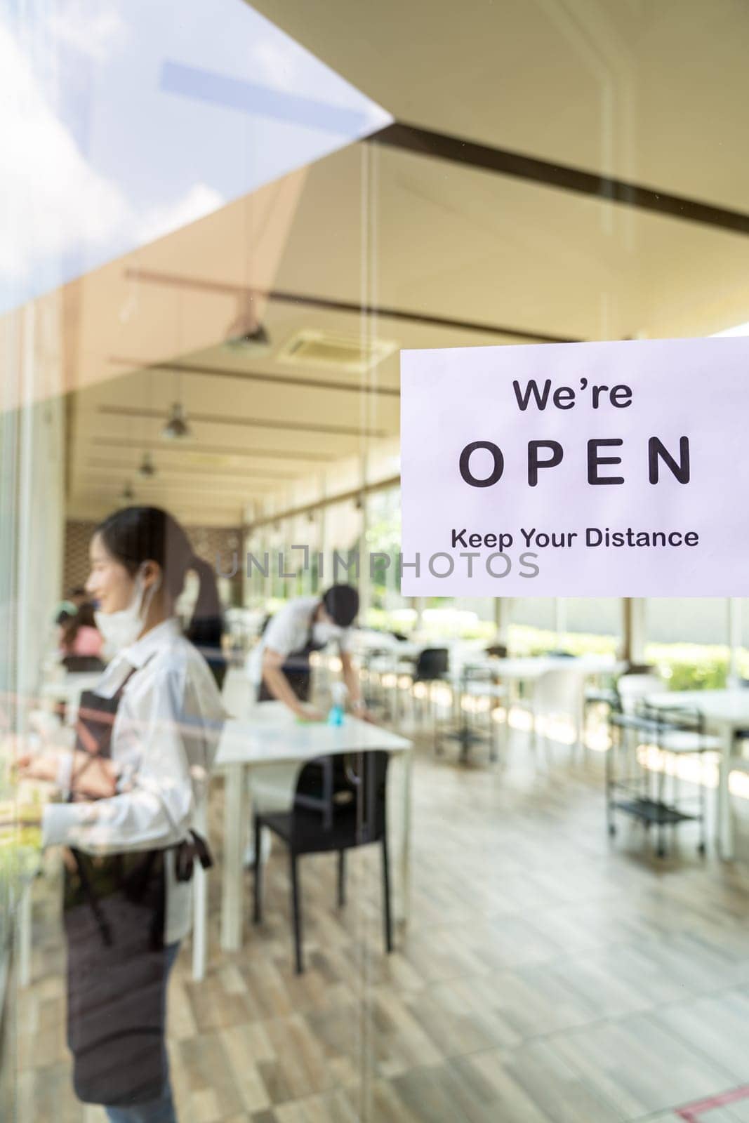 Reopening restaurant signage with social distance for new normal restaurant with background of asian waiter and waitress prepare restaurant before open. New normal restaurant lifestyle concept.
