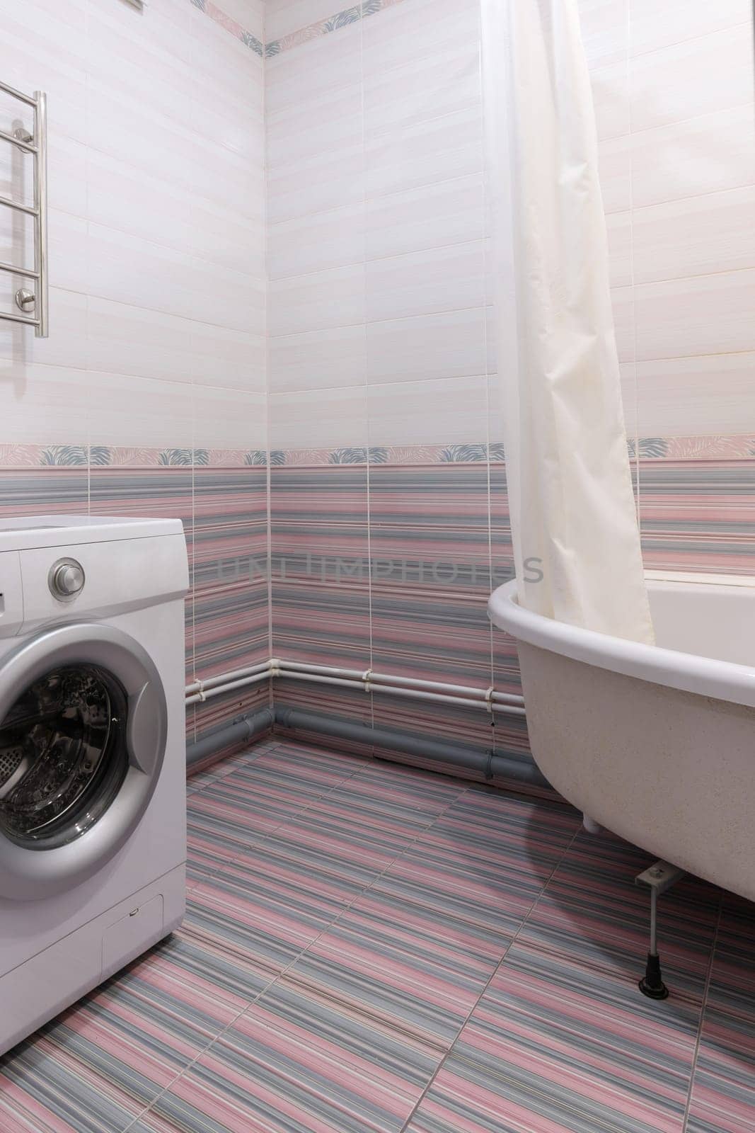 View of an empty corner in the bathroom, with a washing machine and a bathroom on the sides