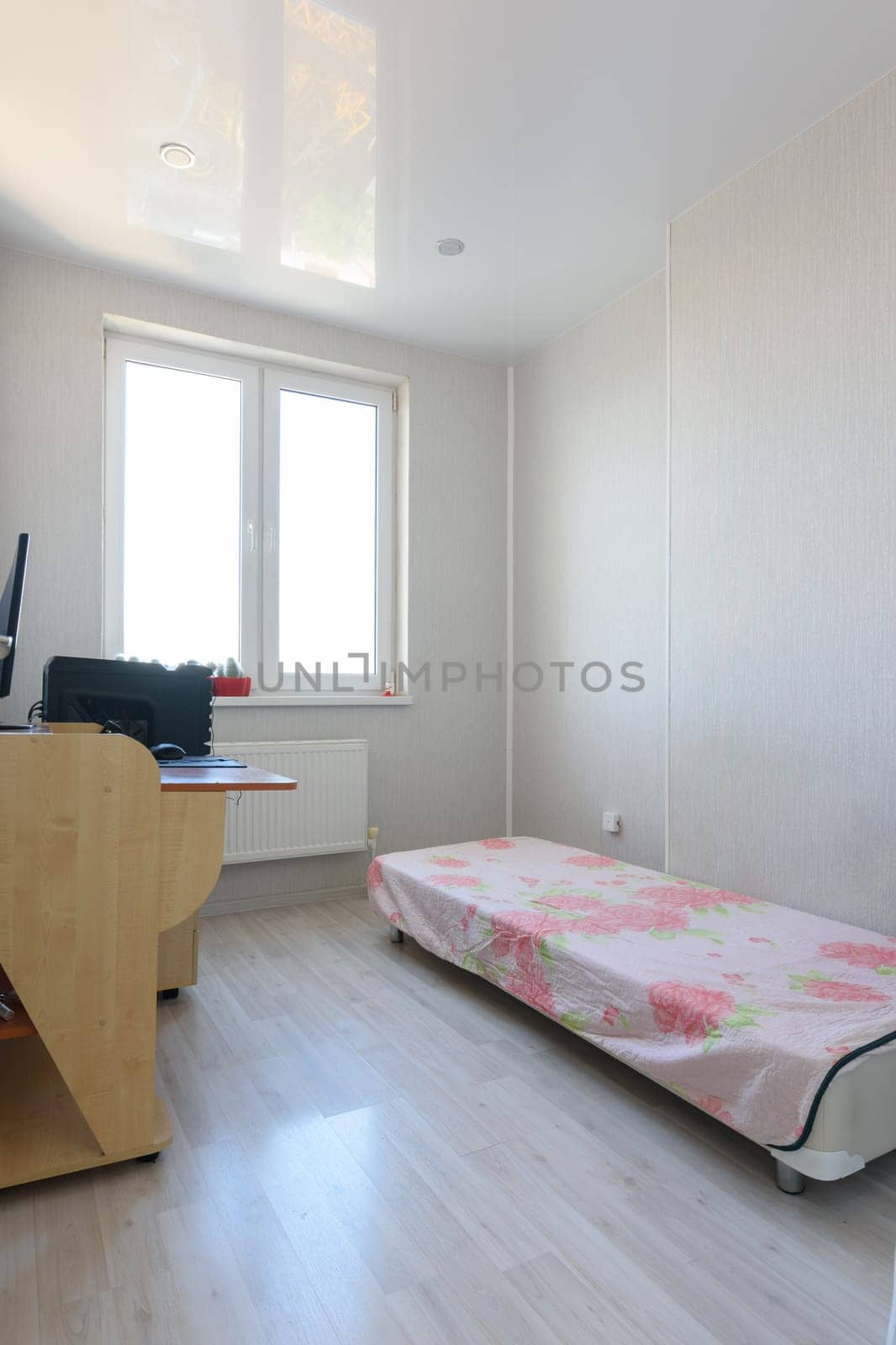 Poor bedroom interior with sparse furniture and a computer table
