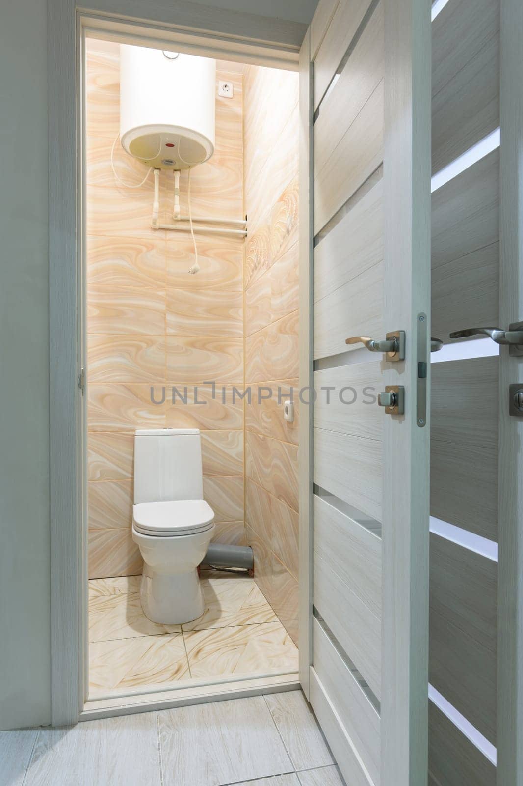 Open door to a small toilet, a water heater is located upstairs