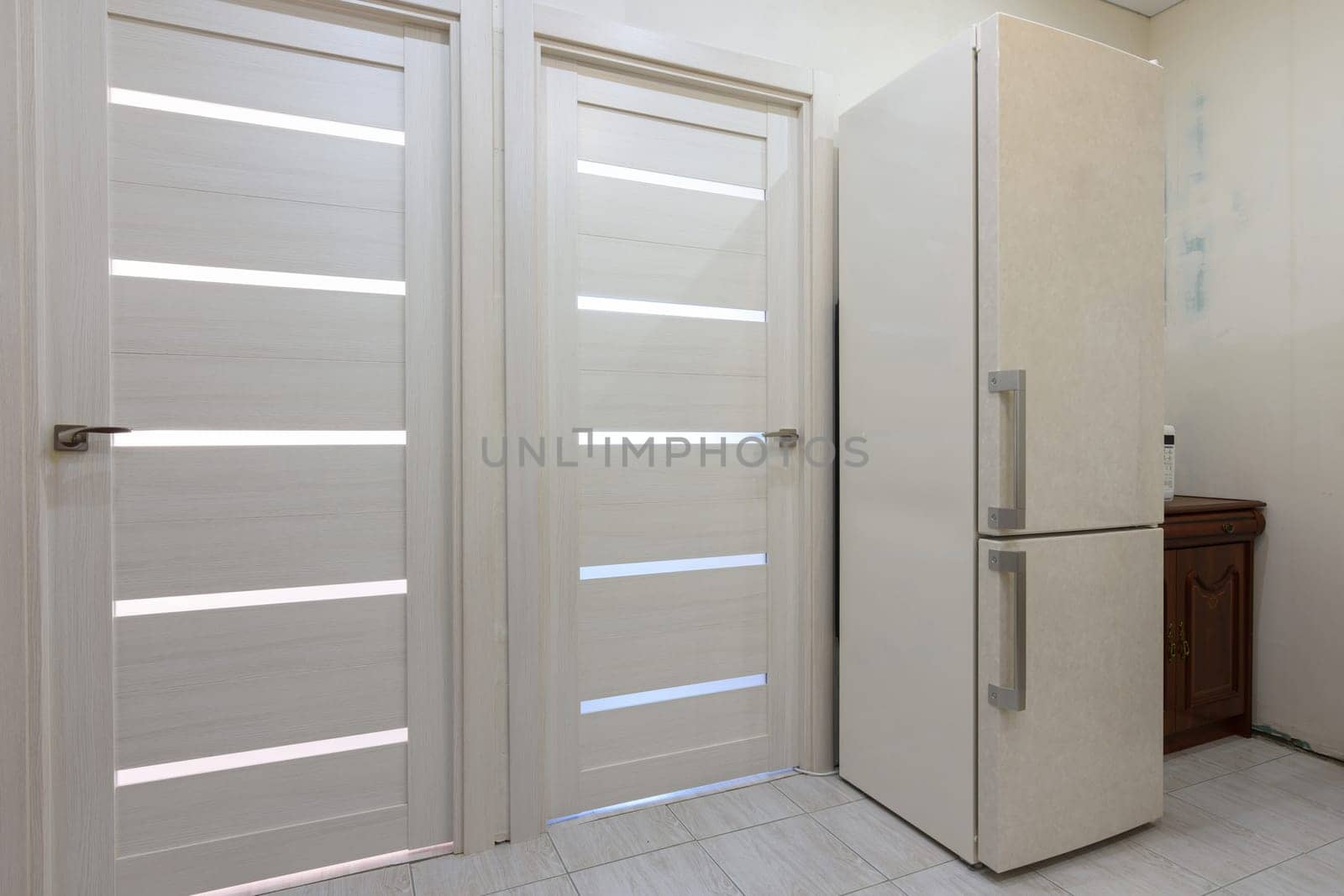 Two interior doors in the apartment, there is a refrigerator on the right