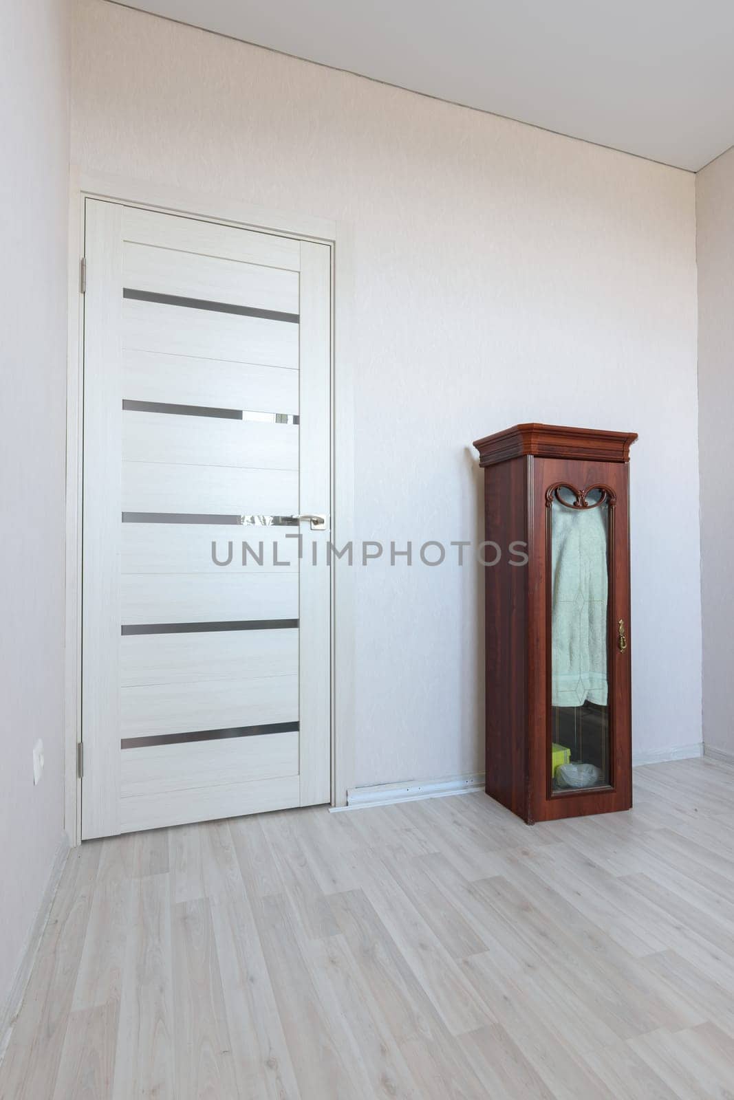 Fragment of an empty room interior with a small cabinet and a door