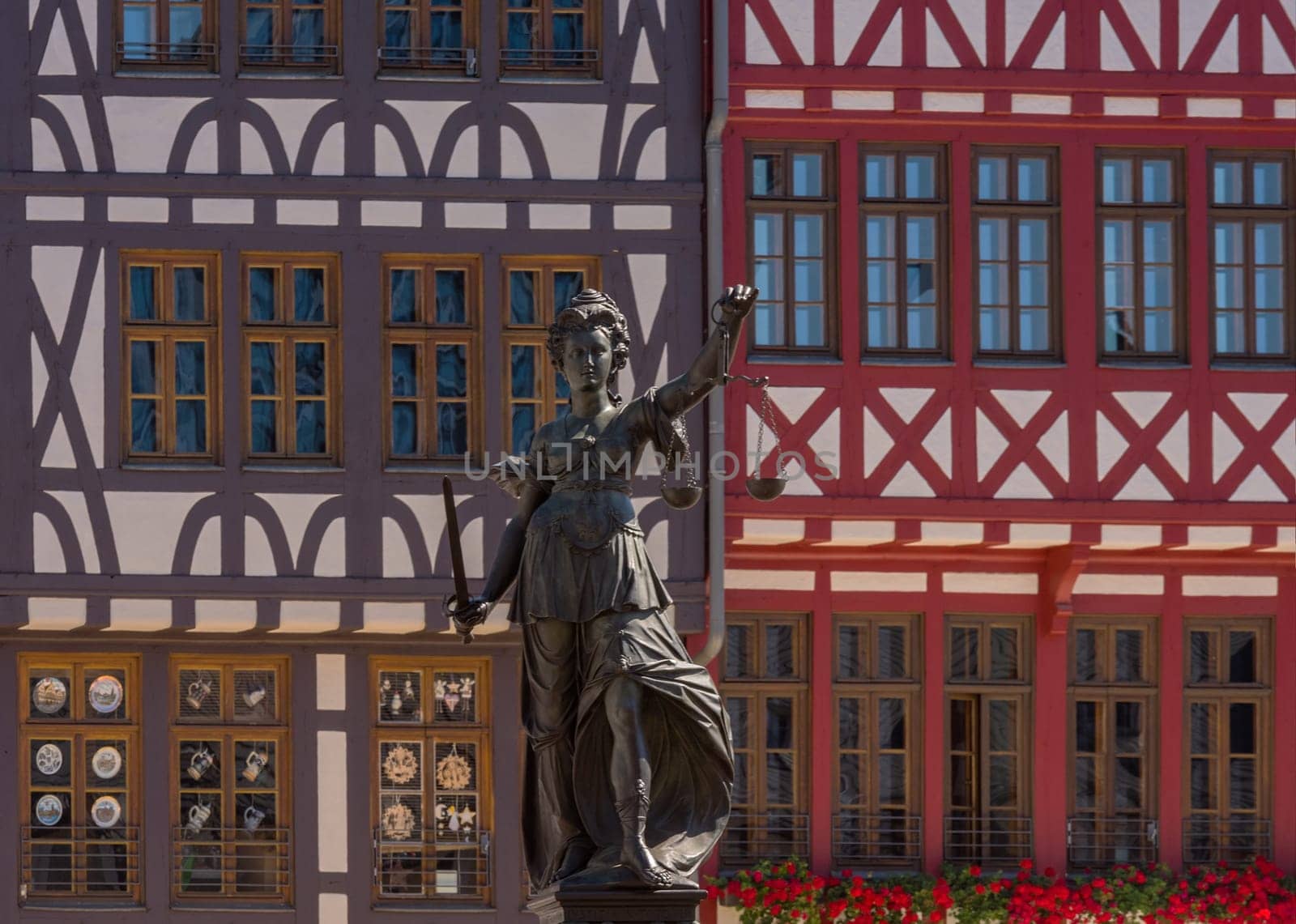 Statue Statue lady justice in front of the half-timbered houses on the Roemerberg in Frankfurt, Germany the judge in front of the half-timbered houses on the Roemerberg in Frankfurt, Germany