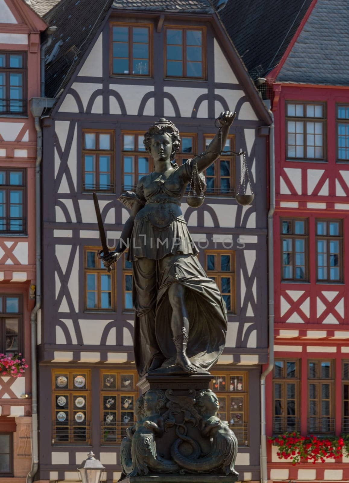 Statue Statue lady justice in front of the half-timbered houses on the Roemerberg in Frankfurt, Germany the judge in front of the half-timbered houses on the Roemerberg in Frankfurt, Germany