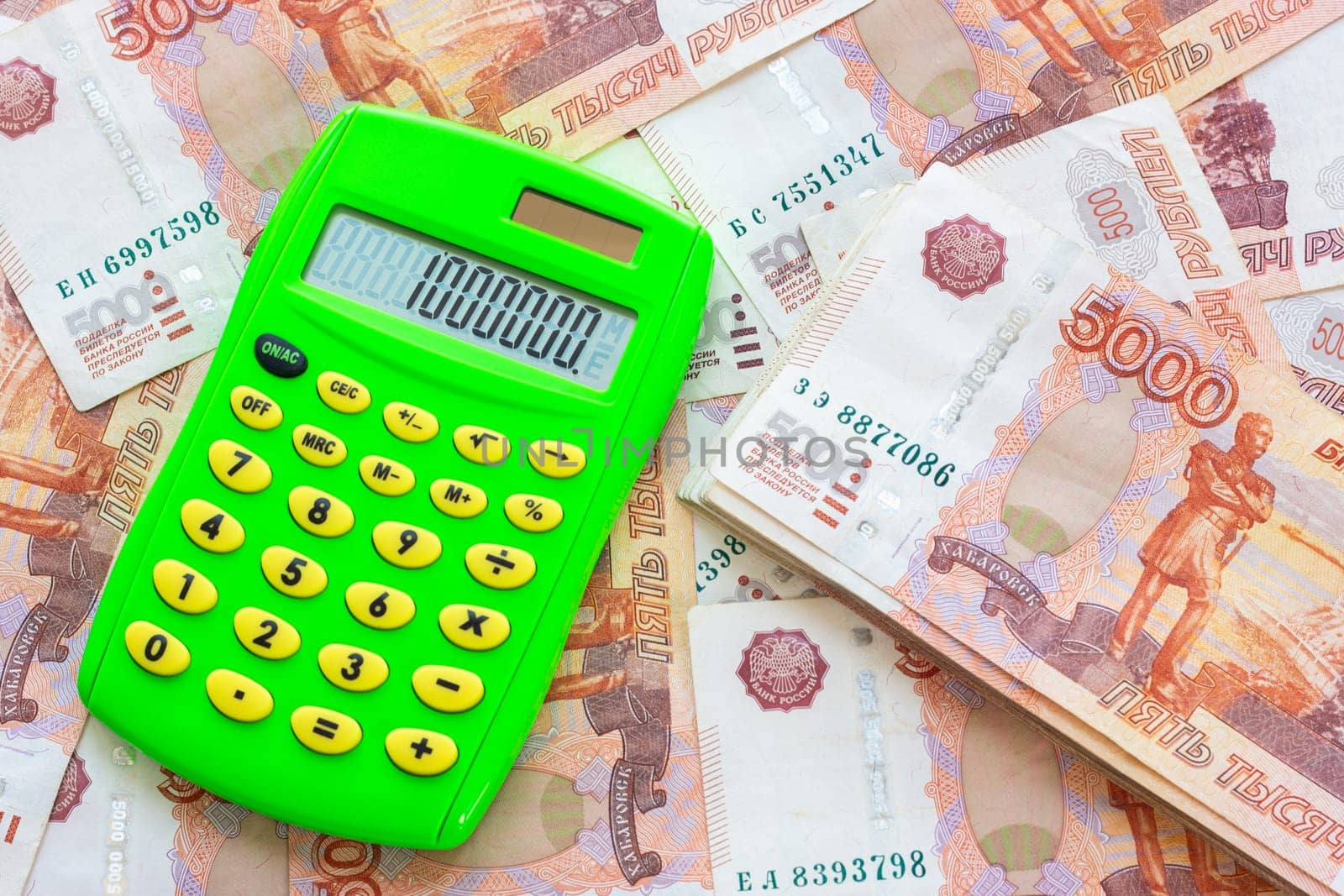 Against the background of money is a bundle of five-thousandth bills and a calculator with the number one million