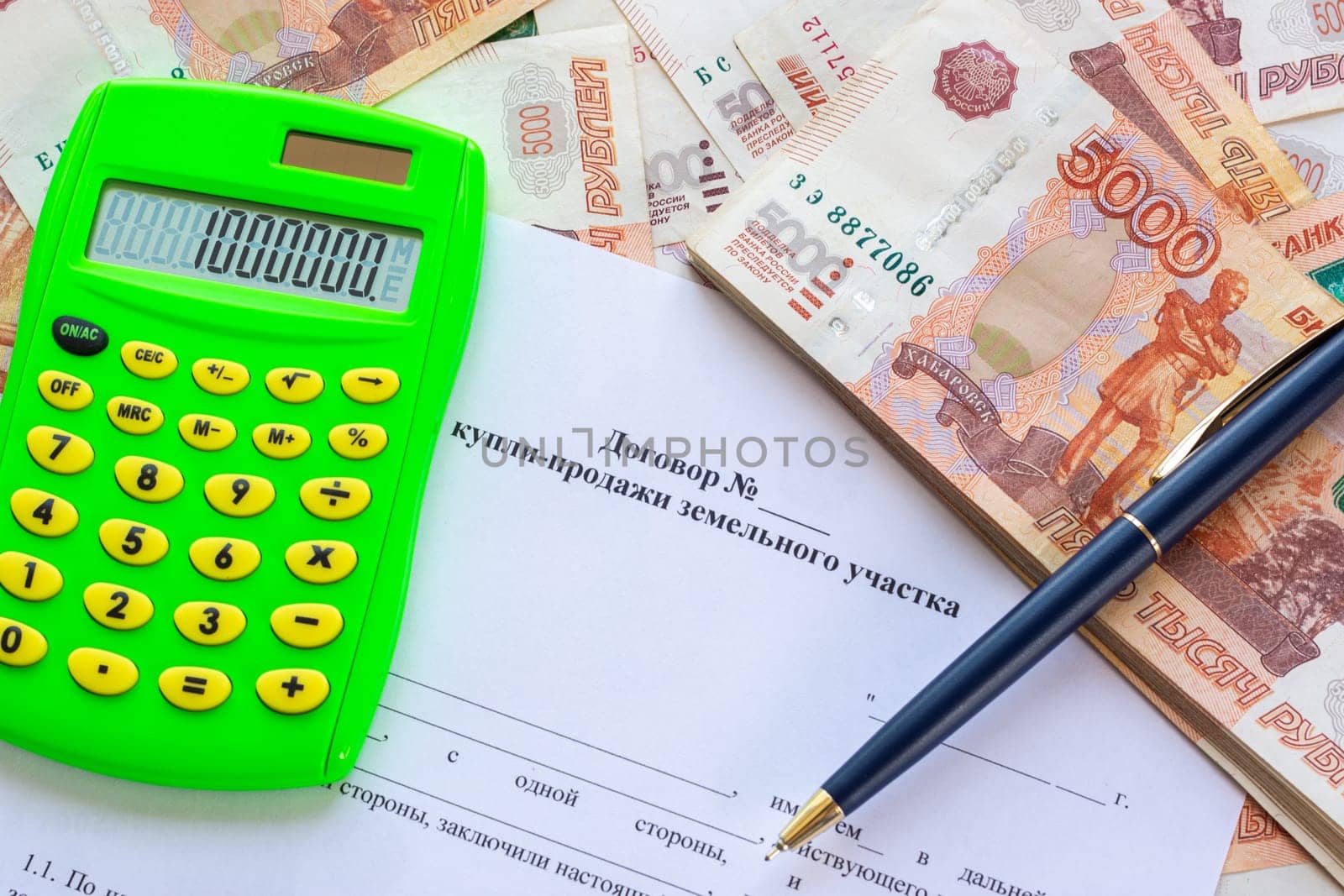 The contract for the sale of the land plot contains a calculator, a wad of money and a pen