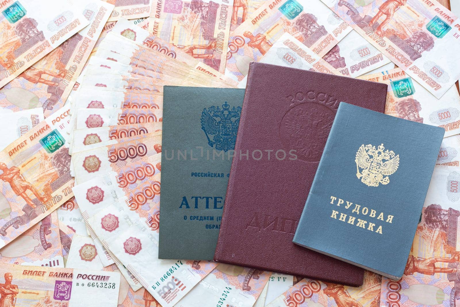 A certificate, a red diploma and a work book are on the five thousandth Russian rubles