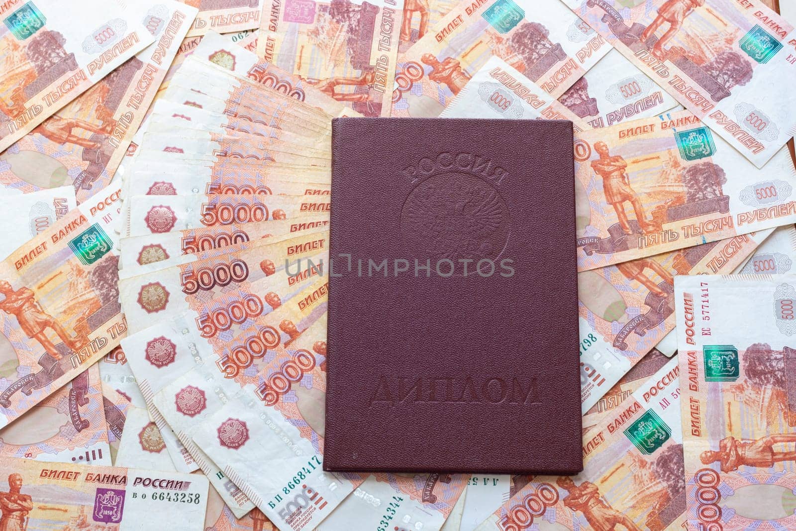Against the background of five-thousandth bills is a red diploma with honors