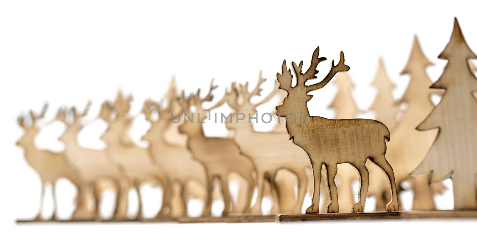 Cut out deer figure made of wood with dark edges and wooden fir trees isolated on white