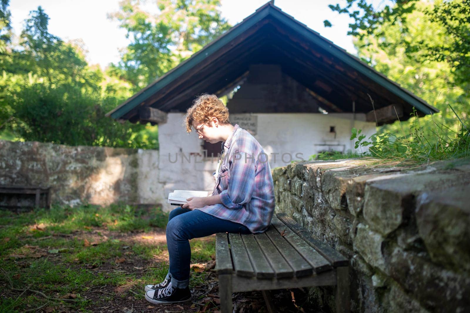 Young female college student studies outside alone on a park bench. Full frame, natural light with copy space.
