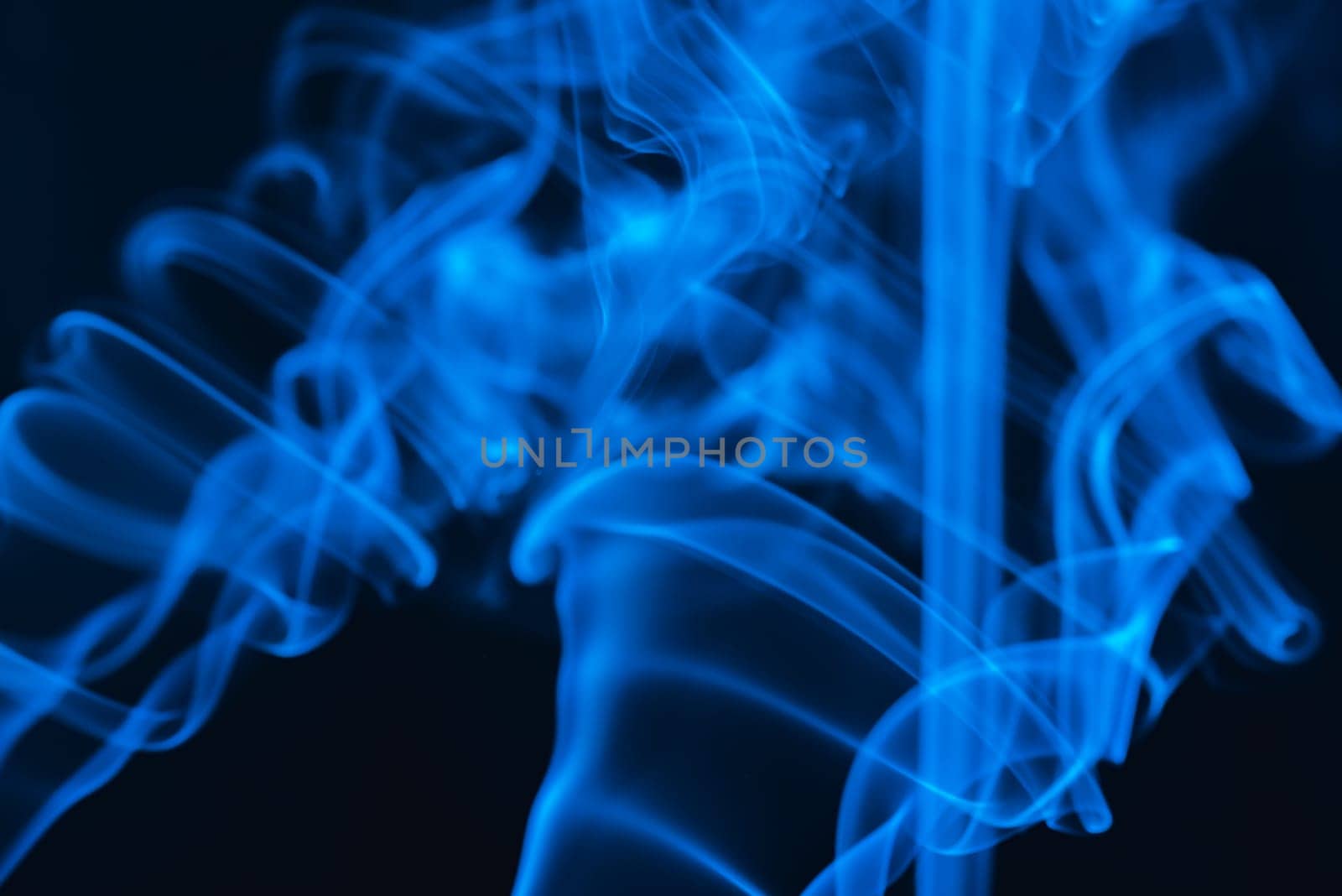 Blue abstract shaped smoke against black background. Abstract background. Selective focus