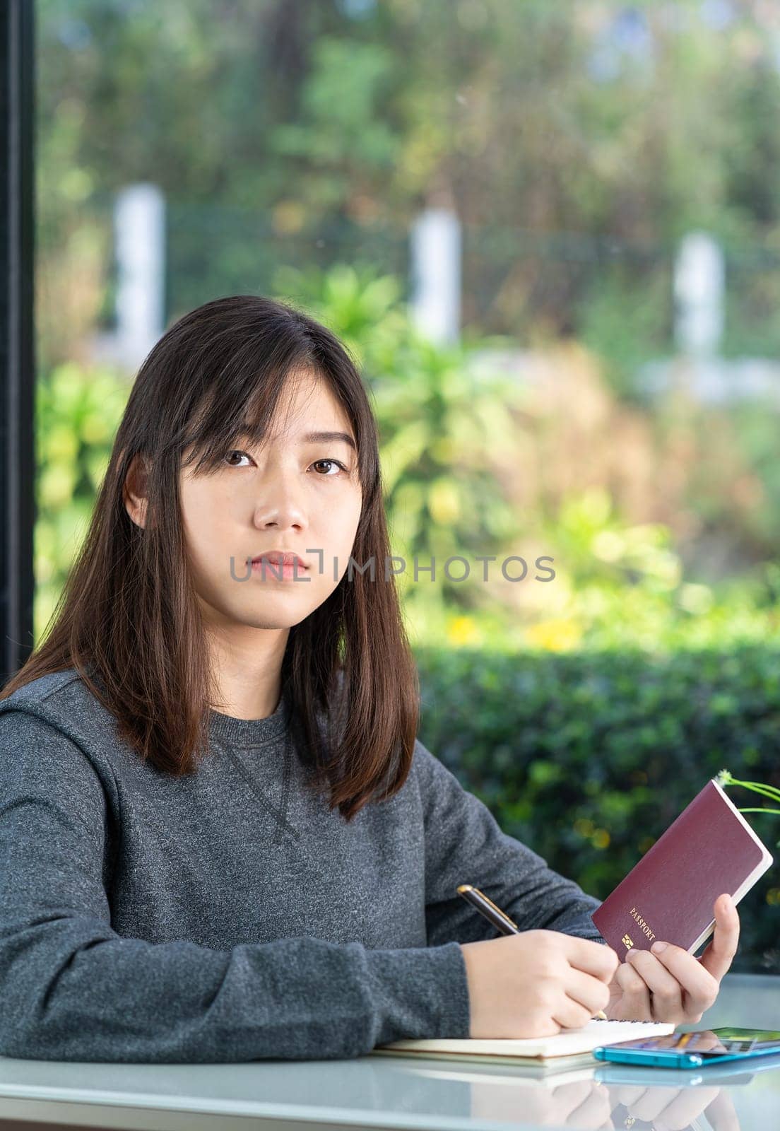 Young woman sitting sholding passport and credit card in home office