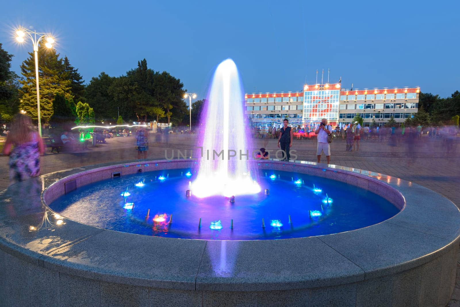 Anapa, Russia - July 17, 2020: A small fountain and tourists taking pictures of it in front of the Sovetov Square in Anapa
